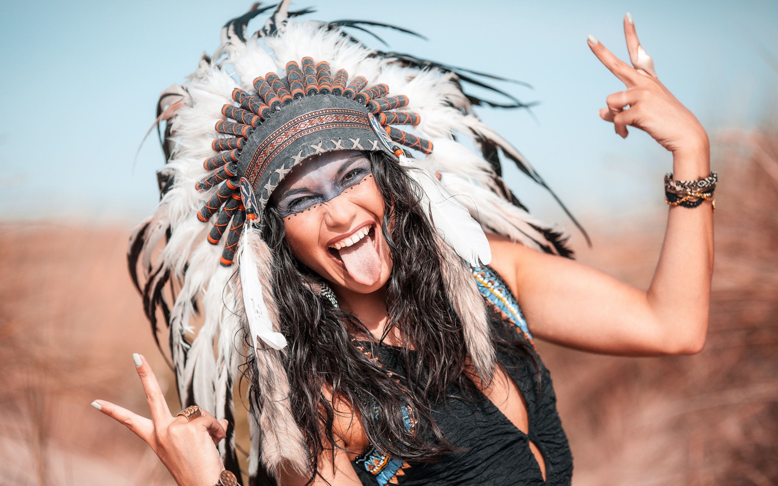 Веселая девушка с высунутым языком в костюме индейца