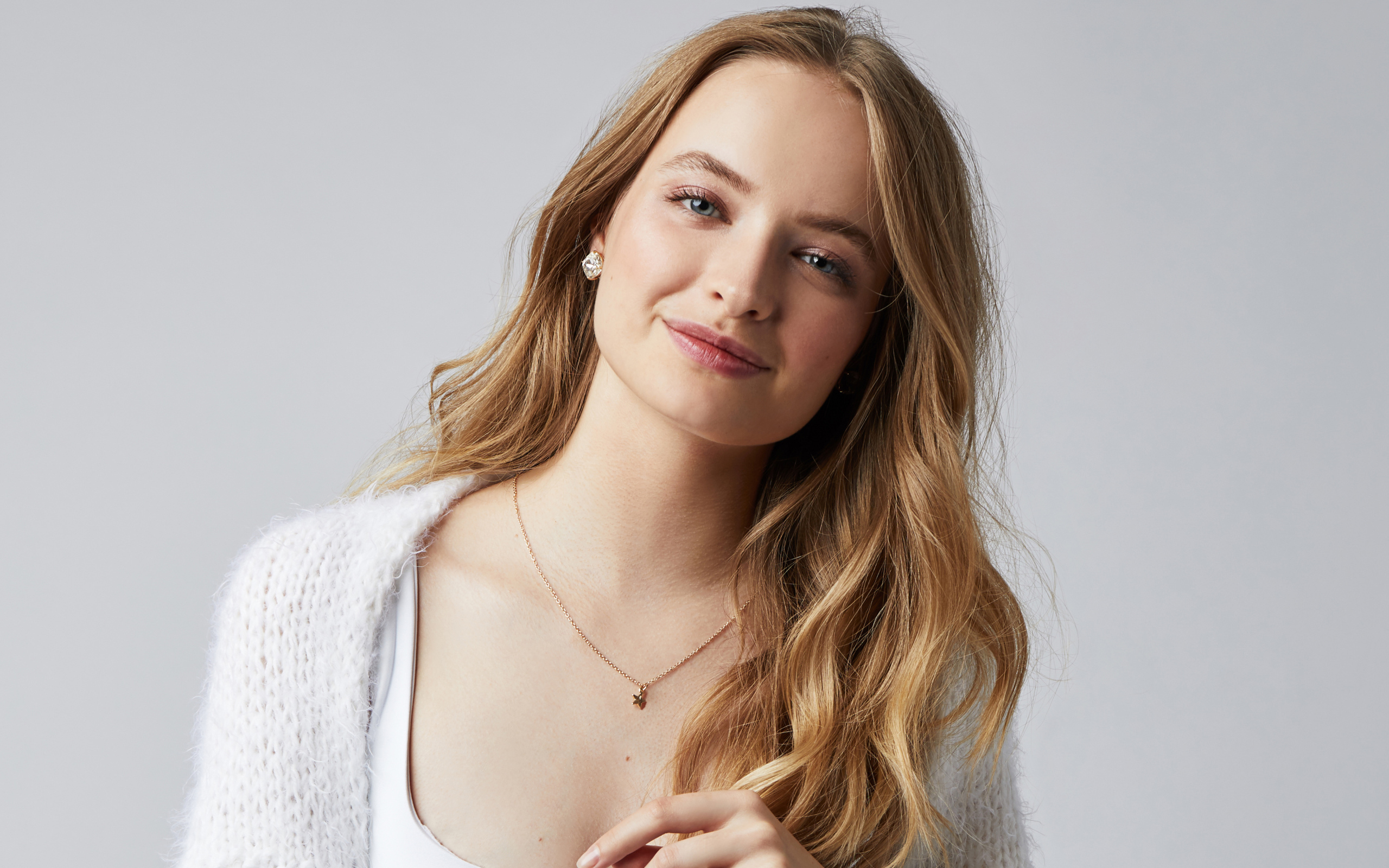 Нежная улыбающаяся голубоглазая девушка на сером фоне