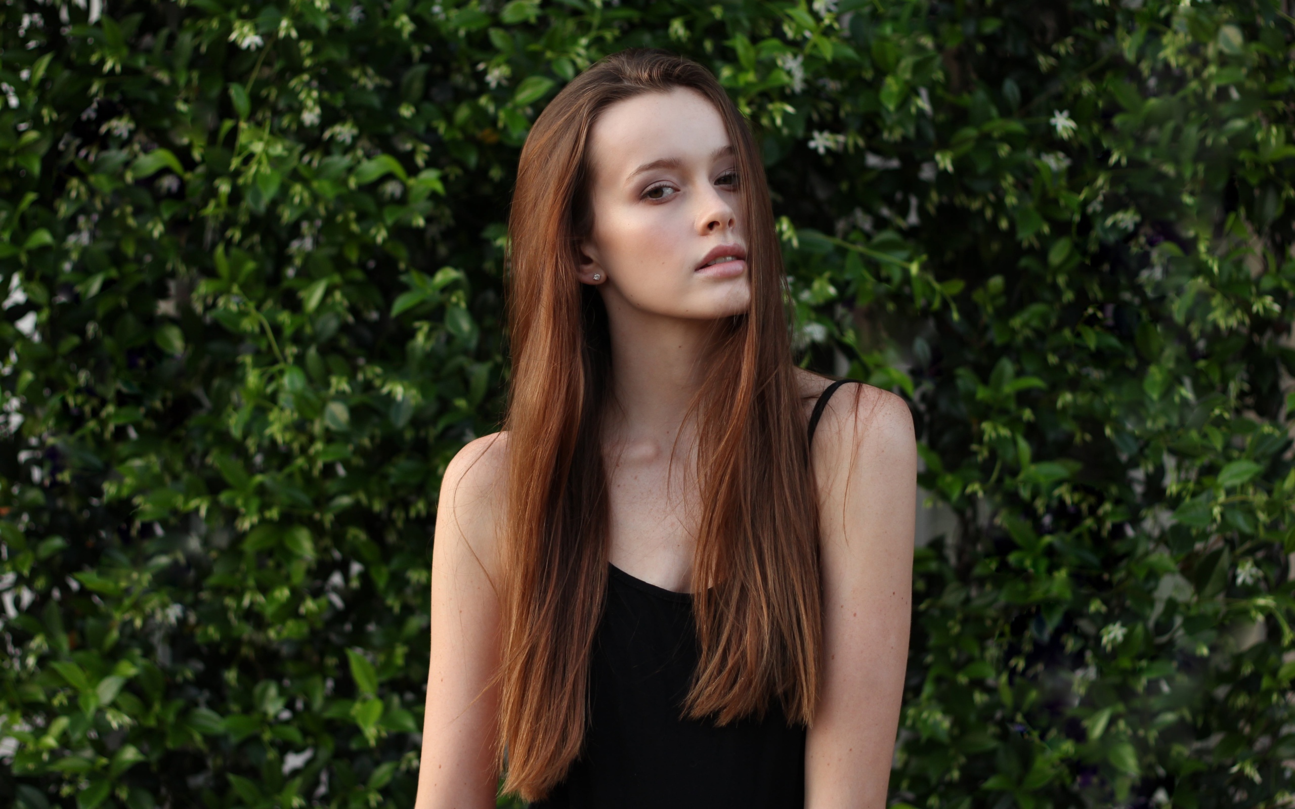 Длинноволосая шатенка на фоне зеленых зарослей
