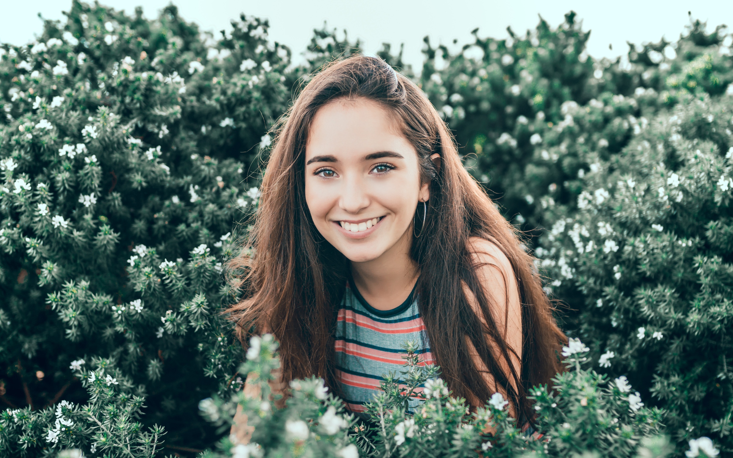 Улыбающаяся девушка сидит в зеленых зарослях 