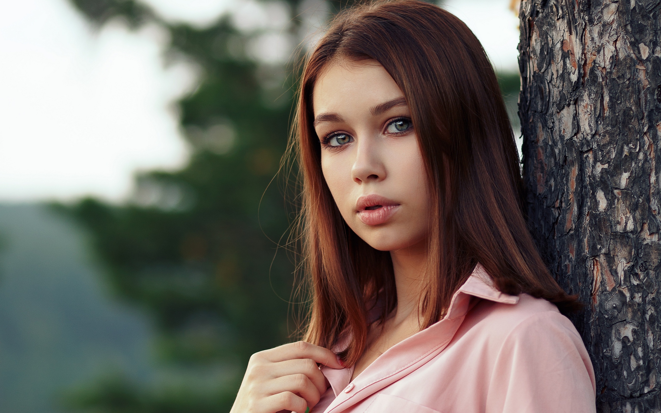 Нежная девушка стоит у дерева