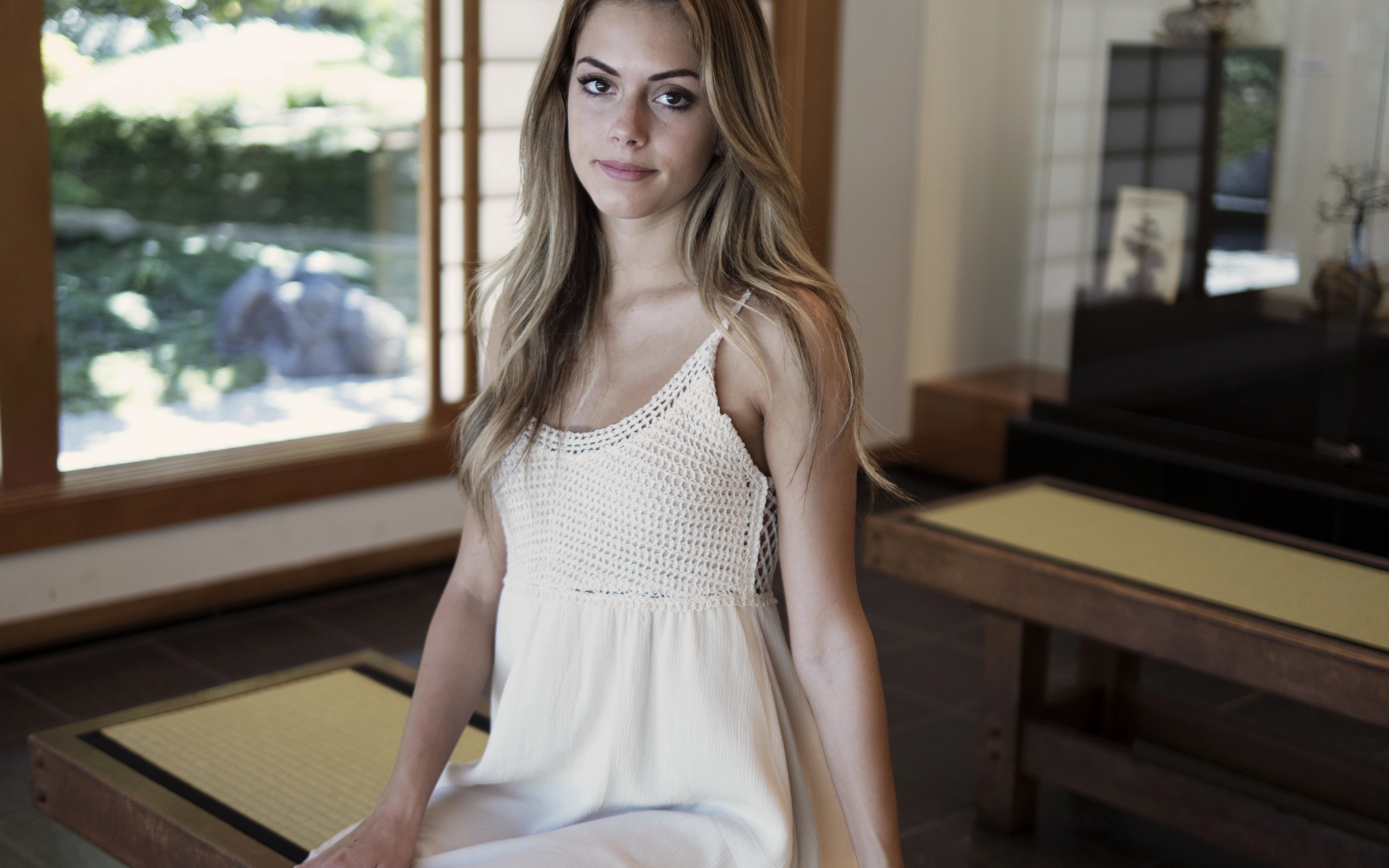 Девушка в белом сарафане сидит на лавке 