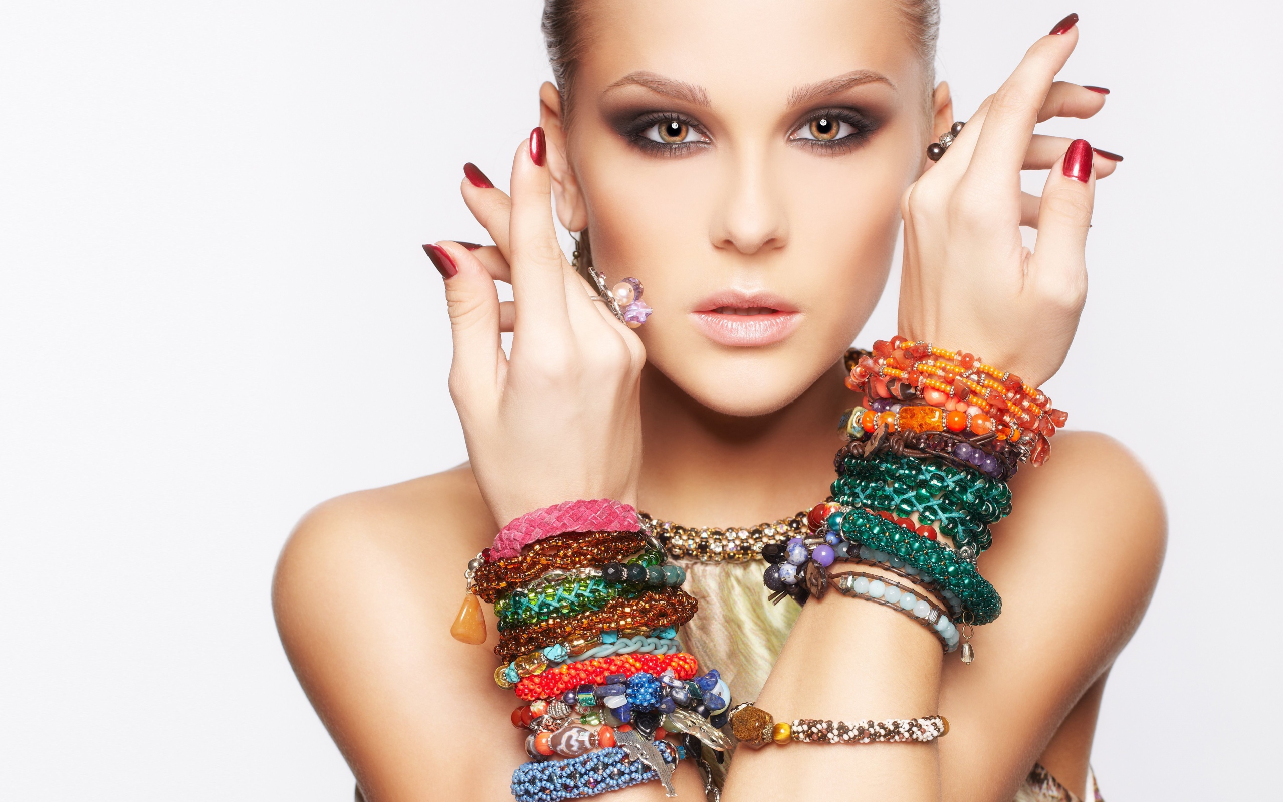 Молодая кареглазая девушка с браслетами на руках на белом фоне