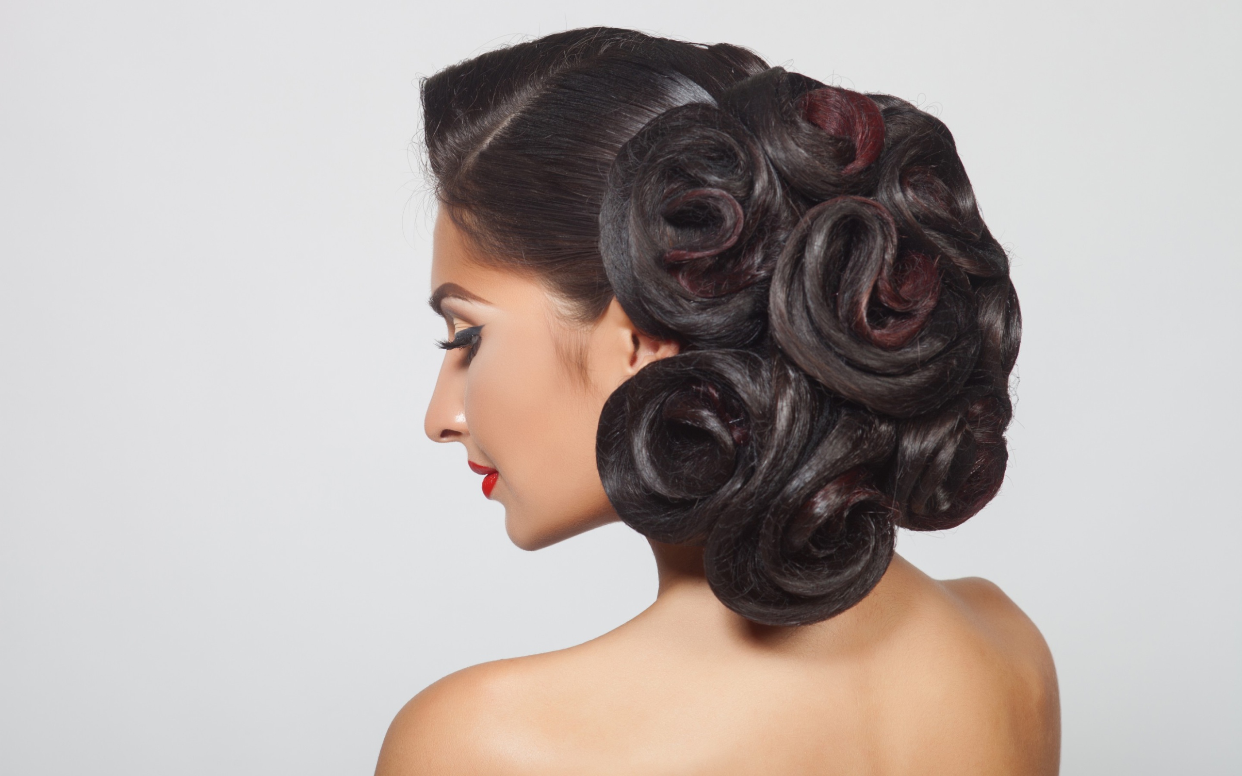 Молодая девушка с красивой прической на сером фоне