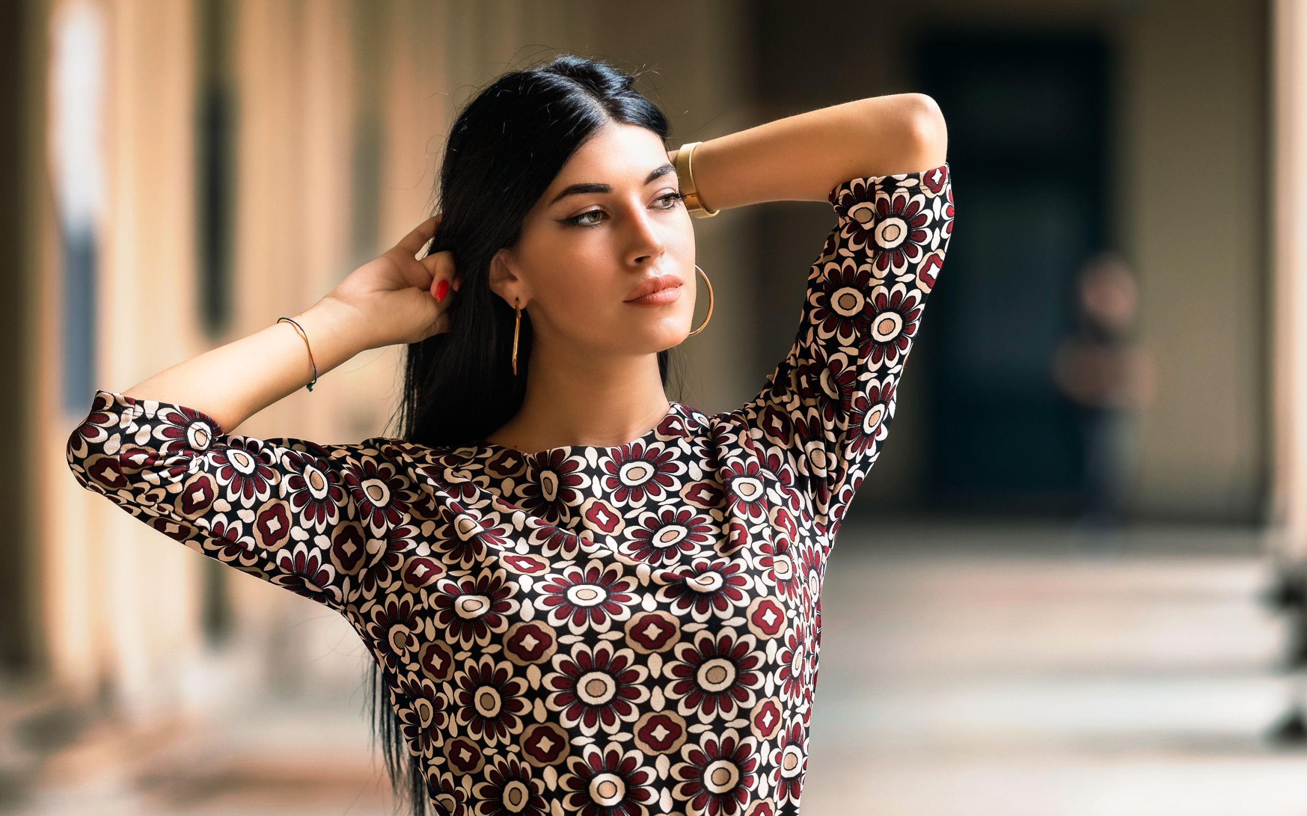 Молодая длинноволосая шатенка с руками в волосах