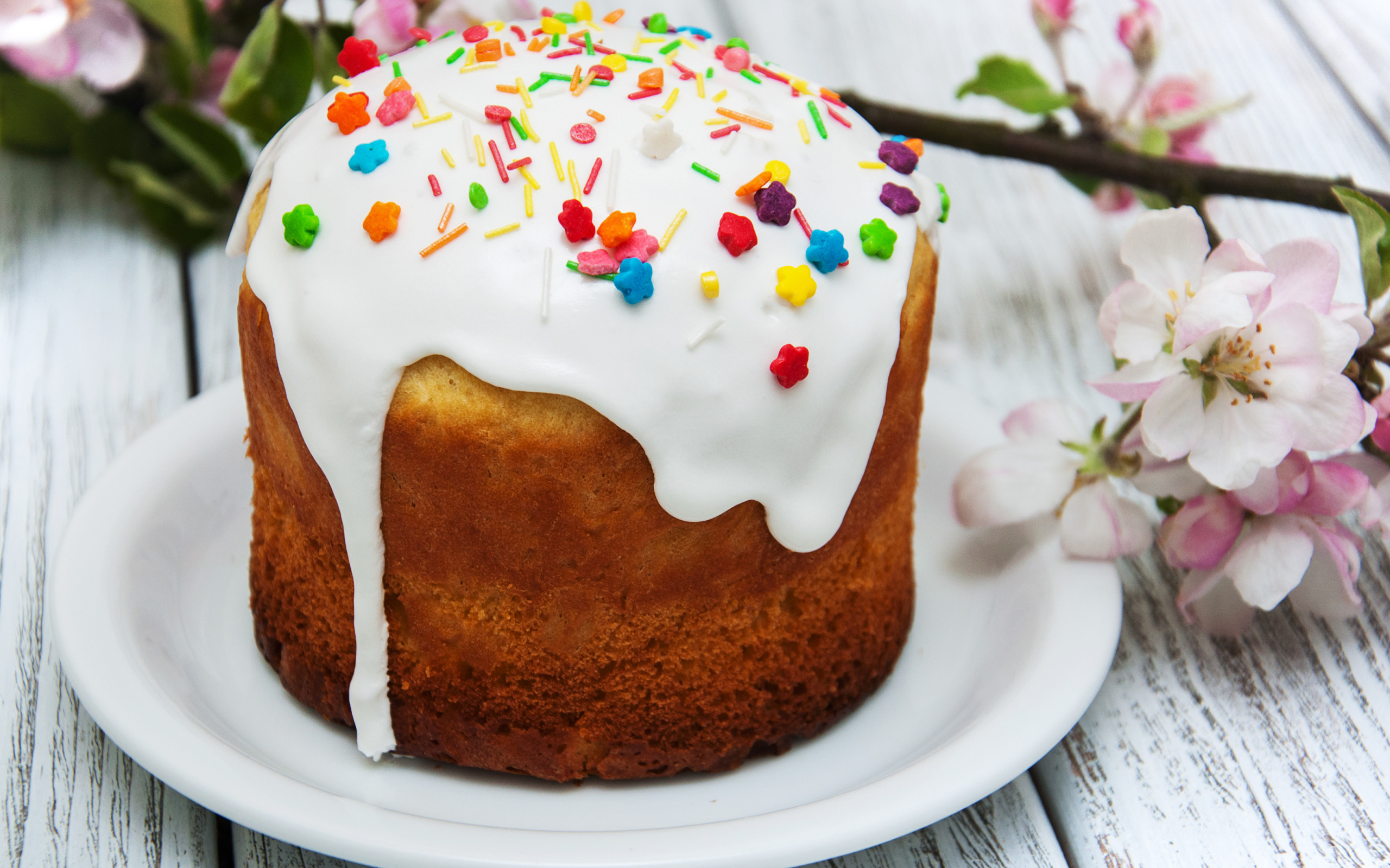 Красивый кулич с белой глазурью на столе с веткой яблони на Великий праздник Пасха