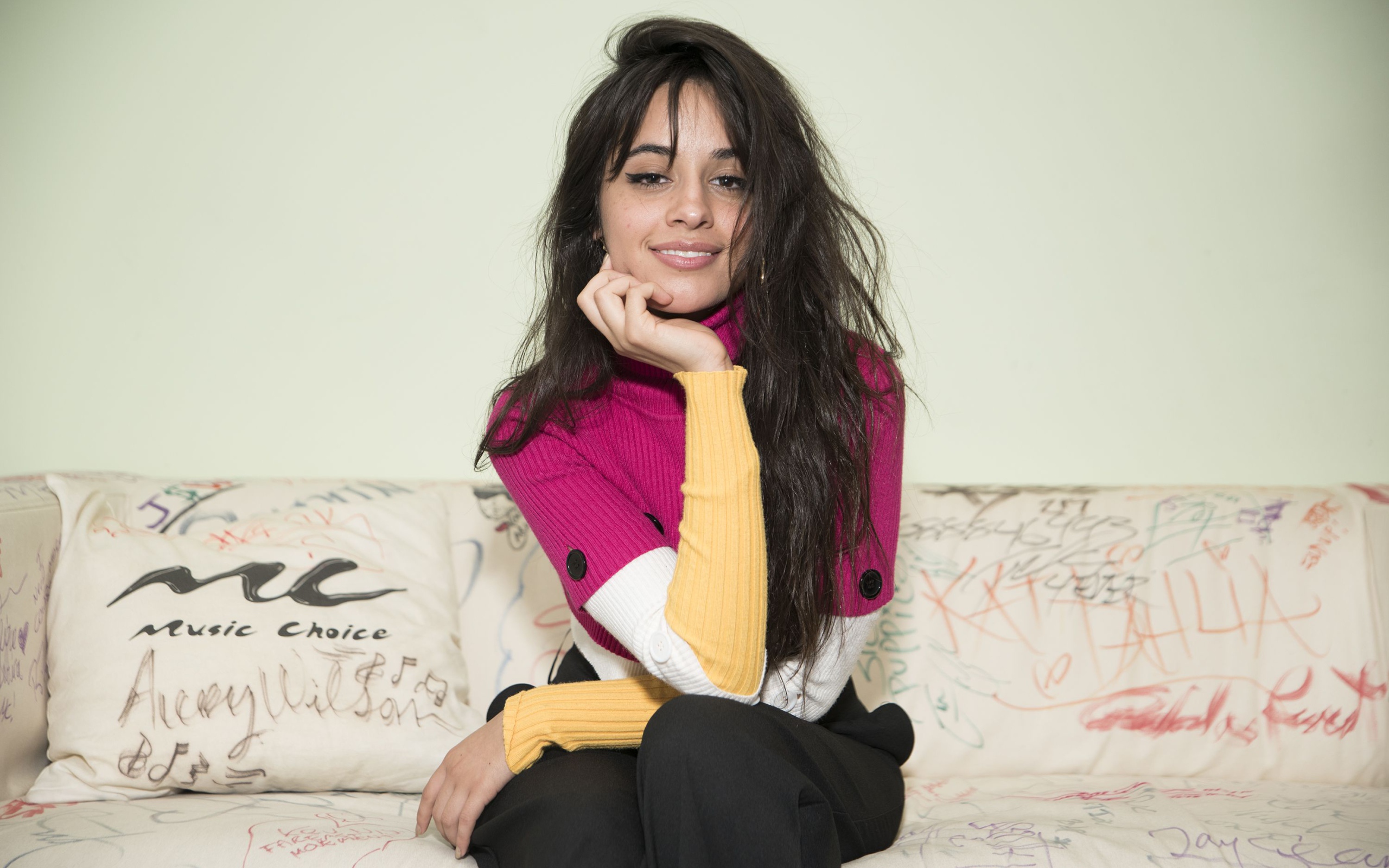 Улыбающаяся Камила Кабельо сидит на диване