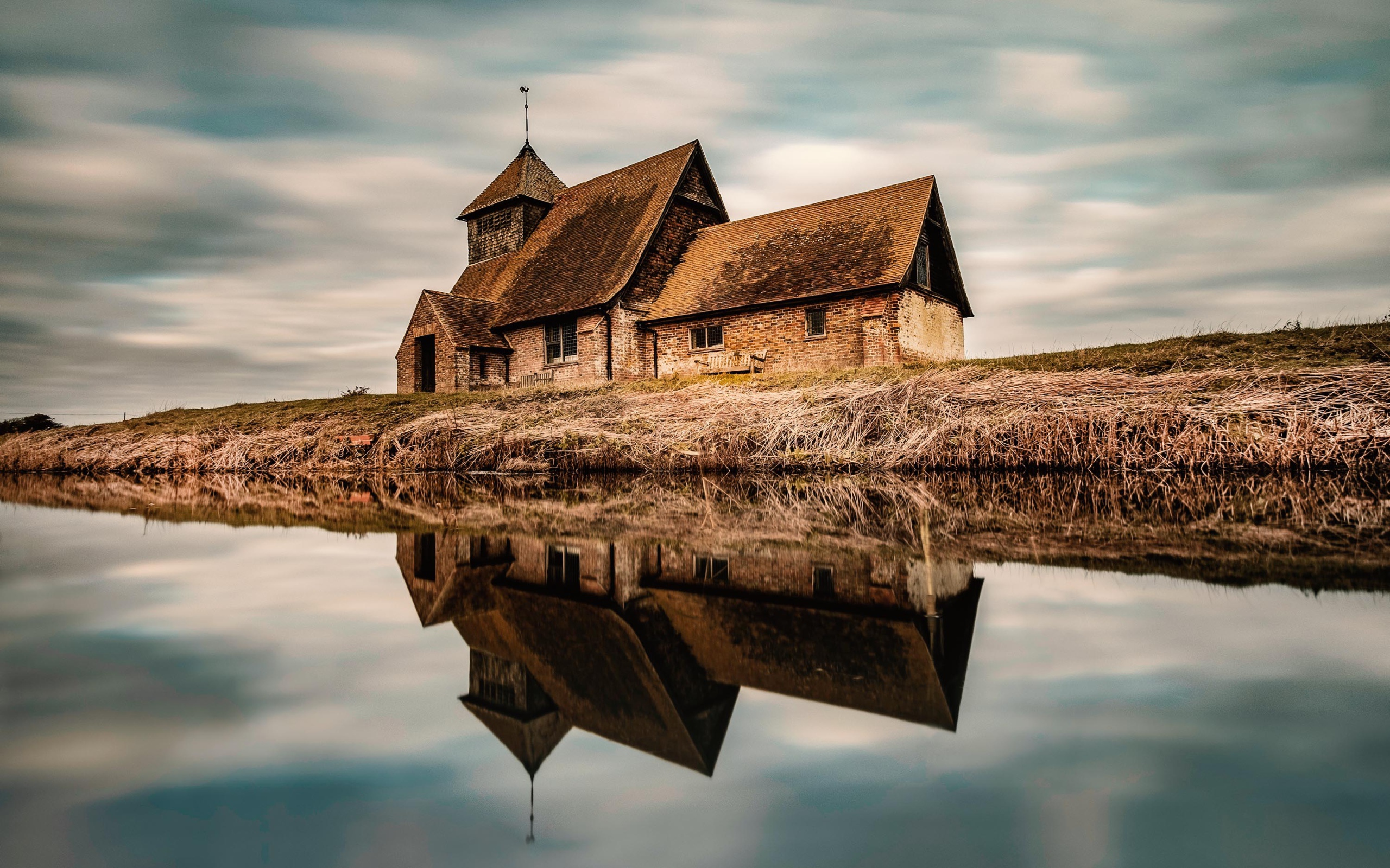 An old house by the river is reflected in the water