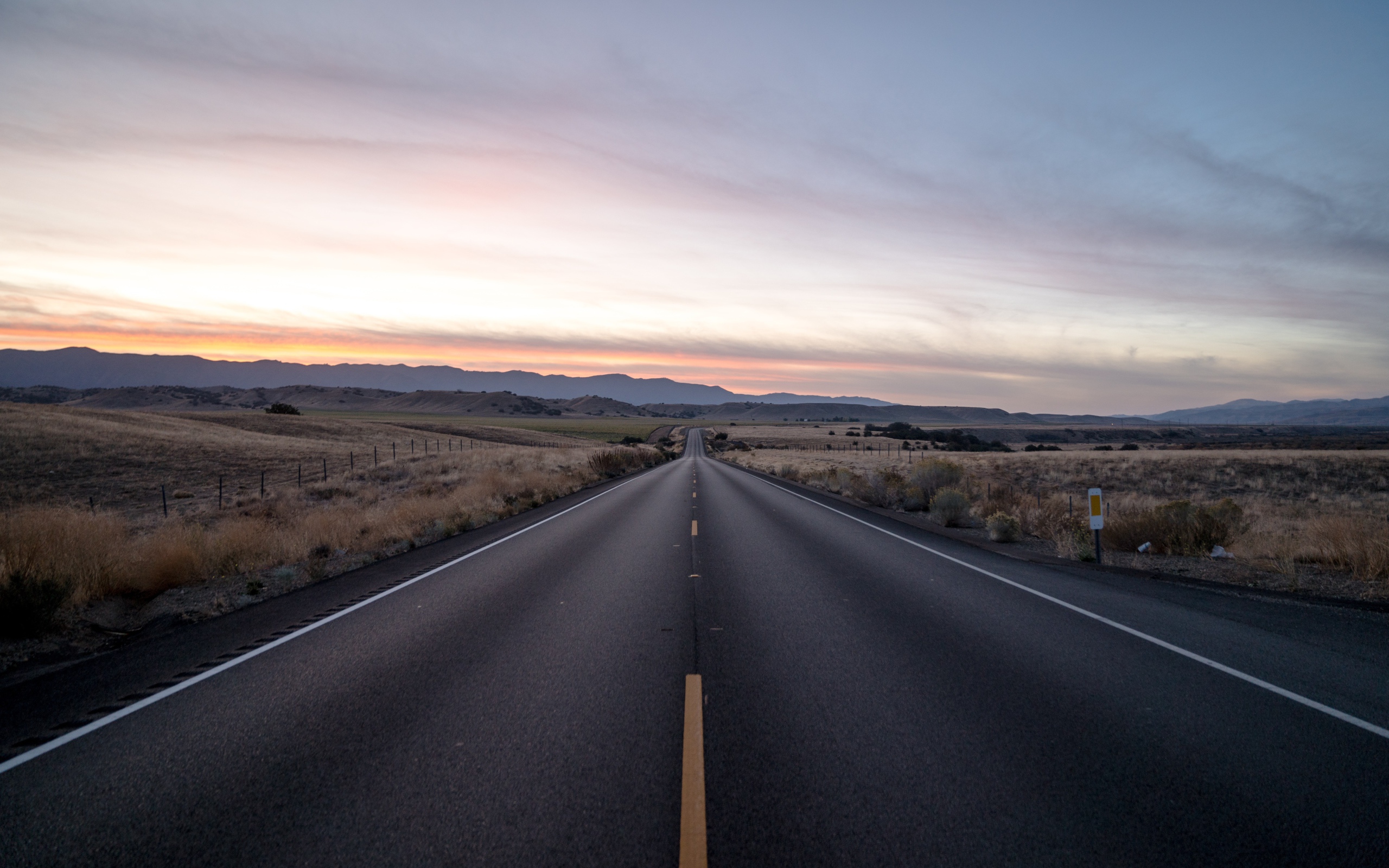 Асфальтная дорога уходит вдаль на фоне неба