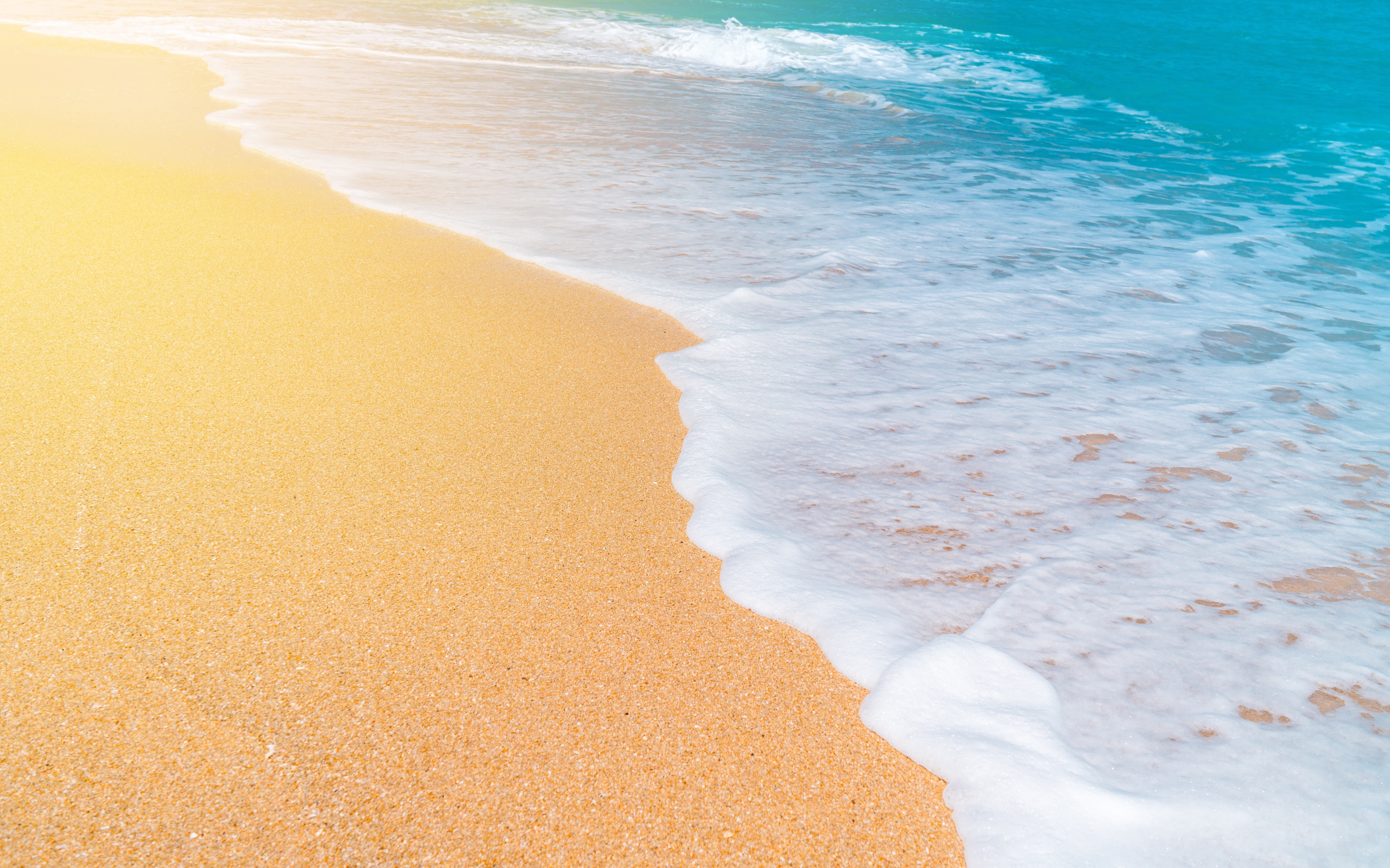 Белые волны океана омывают желтый горячий песок на пляже