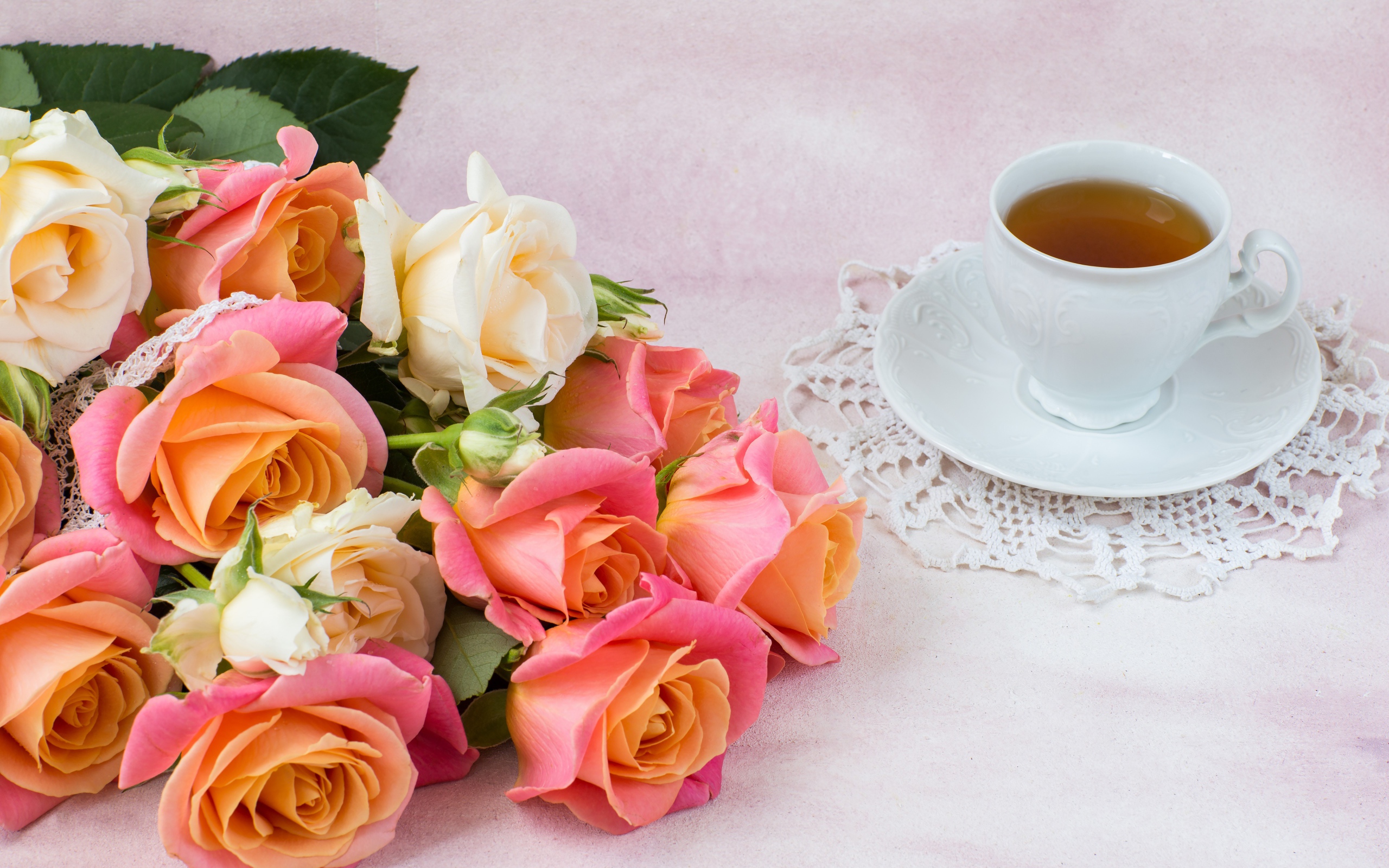 Красивый букет нежных роз на столе с чашкой чая