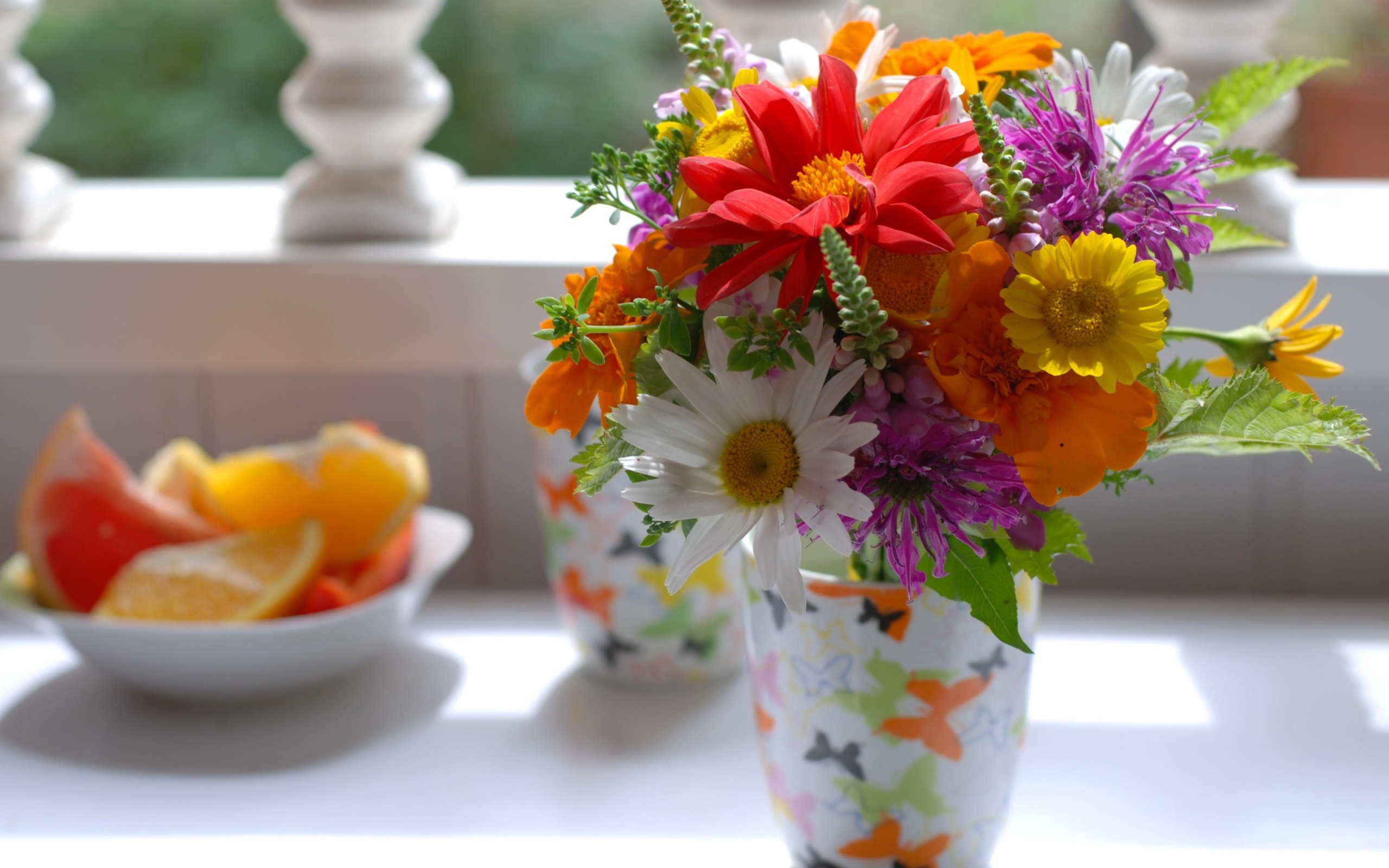 Букет разноцветных  садовых цветов в вазе на столе 