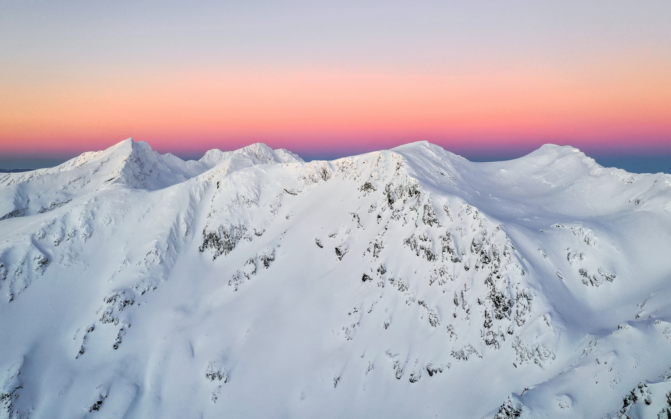 Красивые заснеженные вершины горы на фоне розового неба