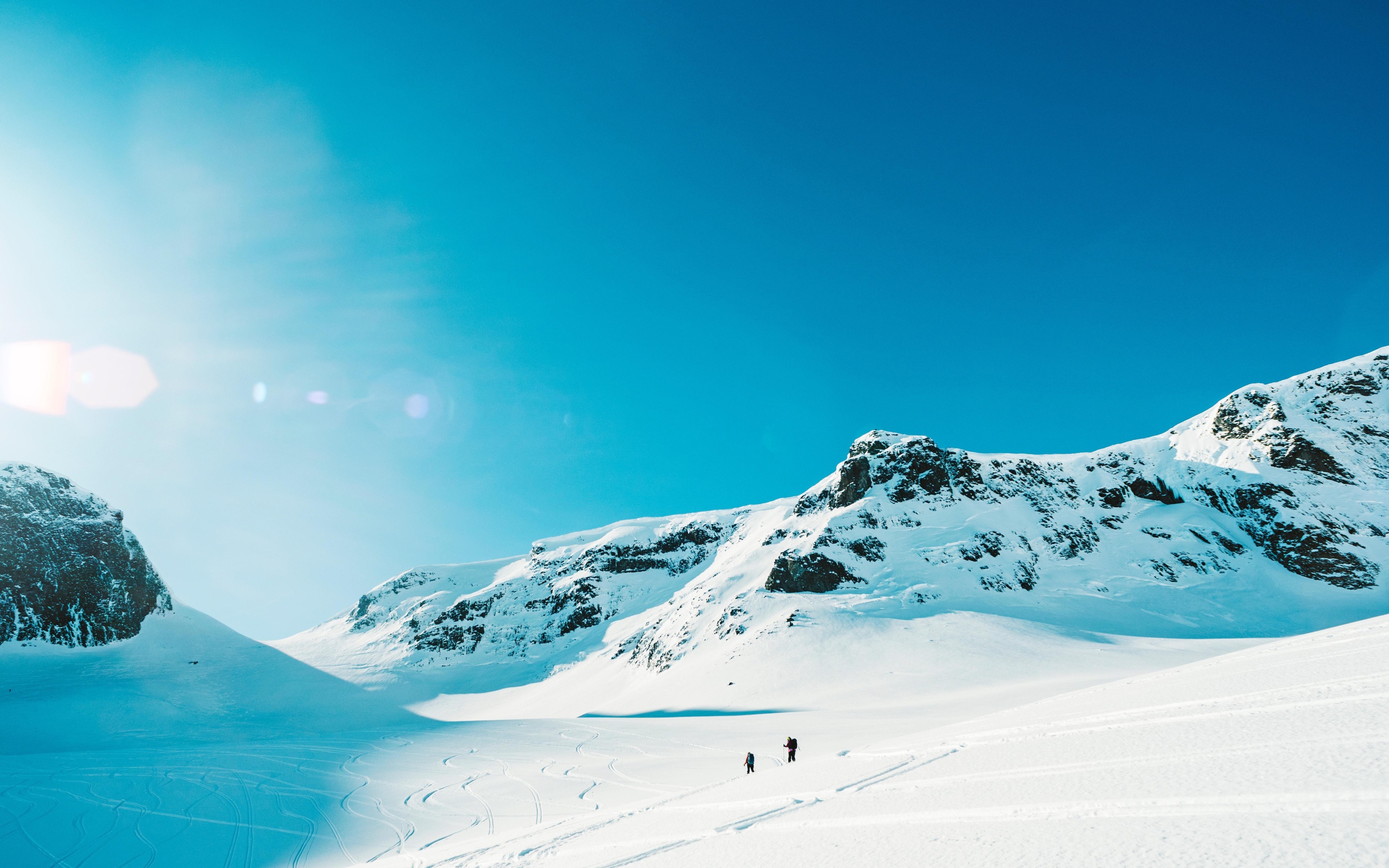 Красивые заснеженные горы под голубым небом в лучах солнца 