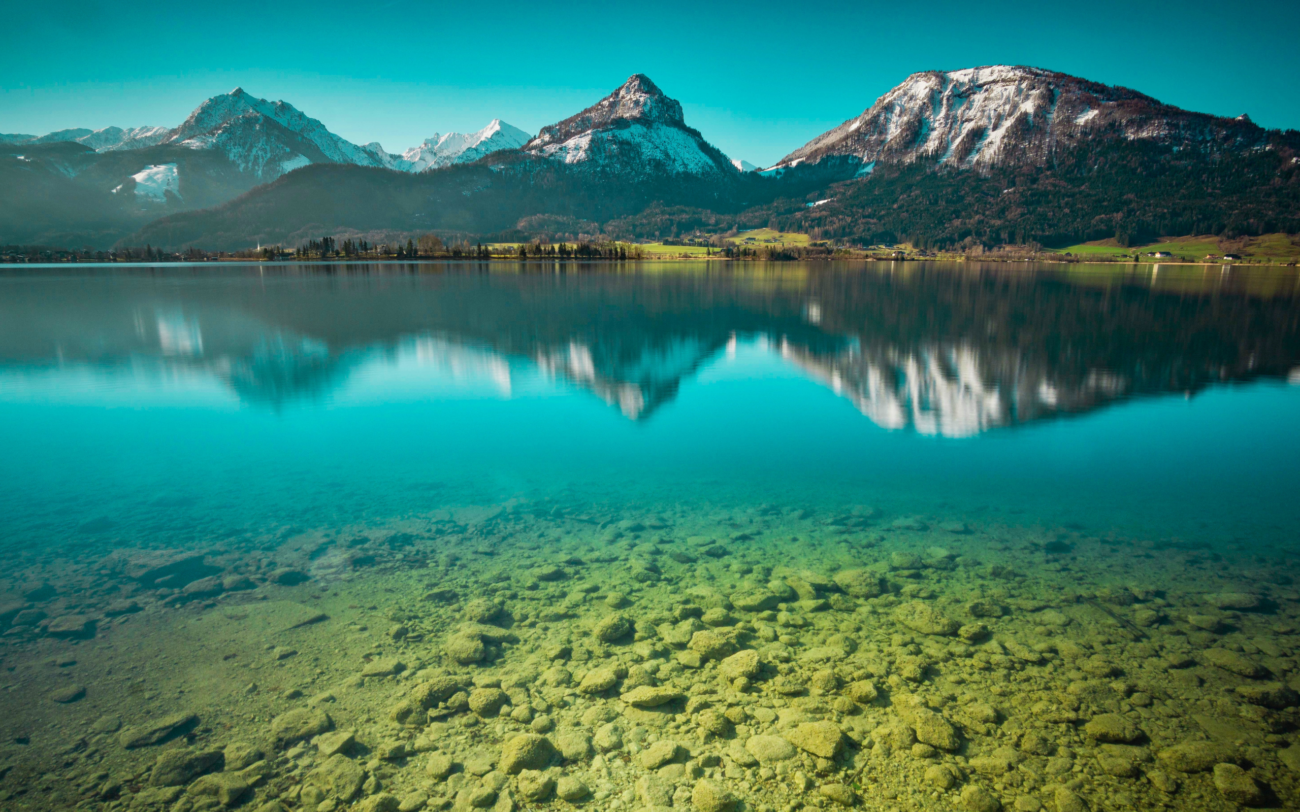 Заснеженные горы отражаются в чистой воде озера 