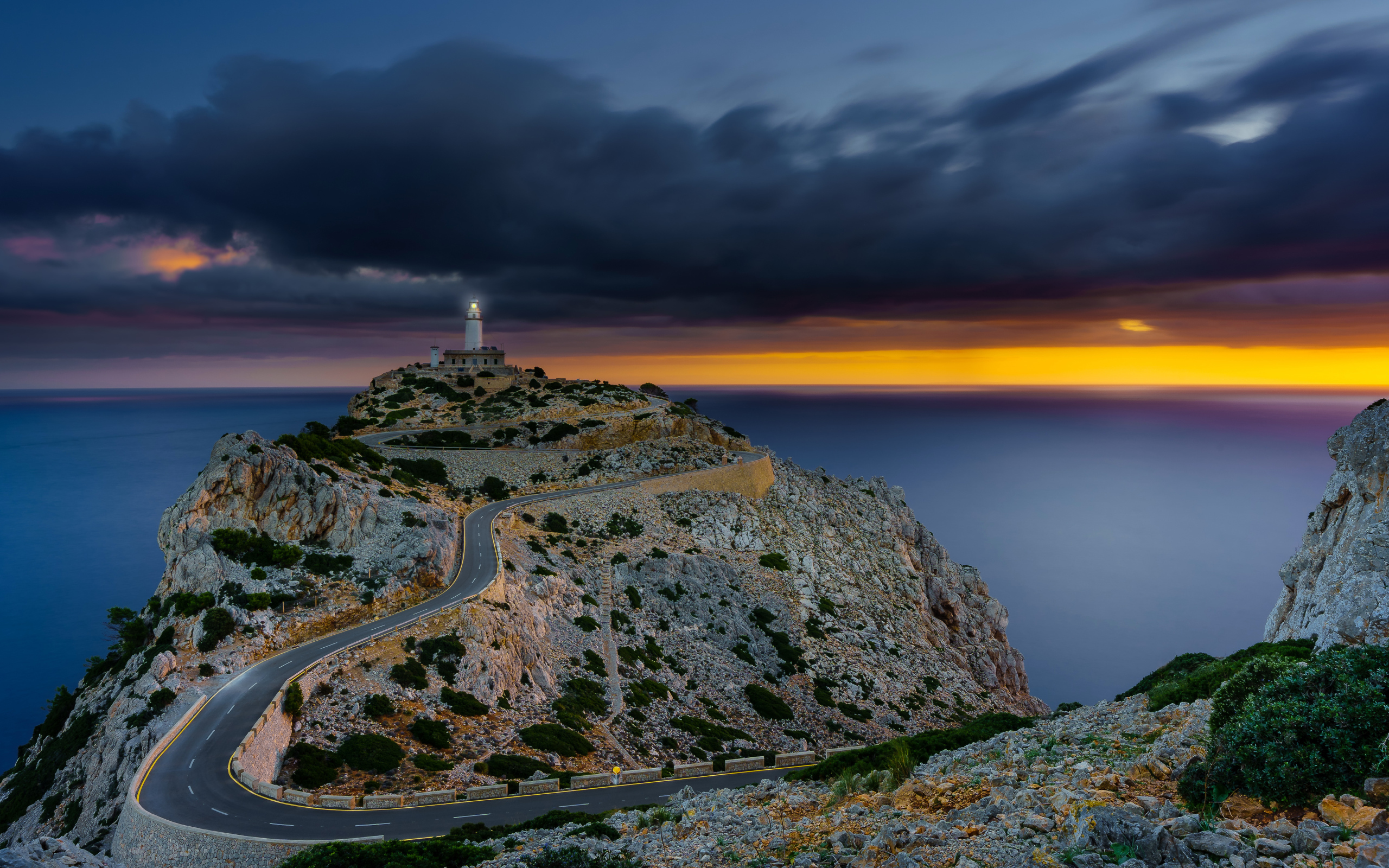 Извилистая дорога ведет к маяку на краю скалы под пасмурным небом