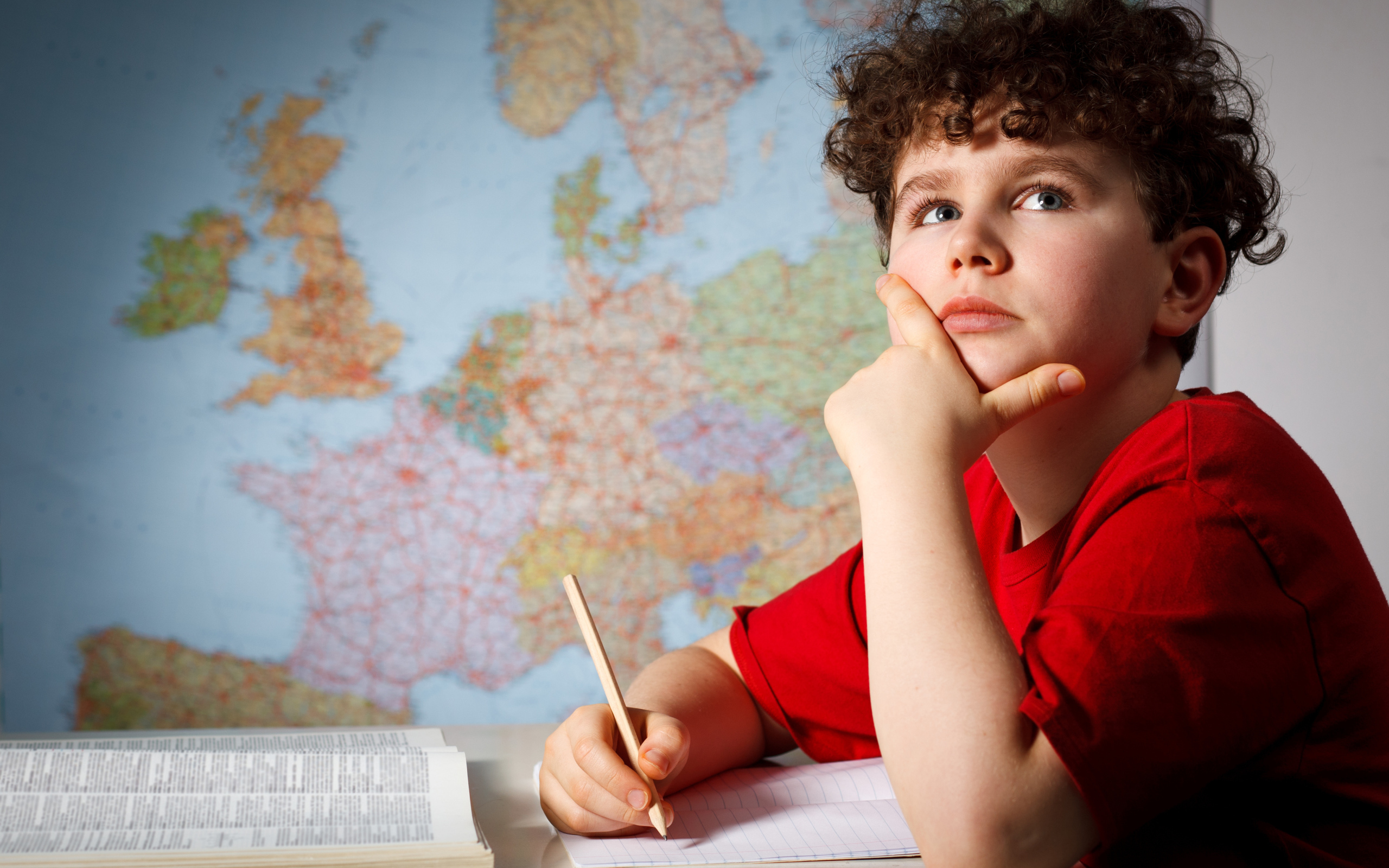 Мальчик ученик делает уроки за столом 