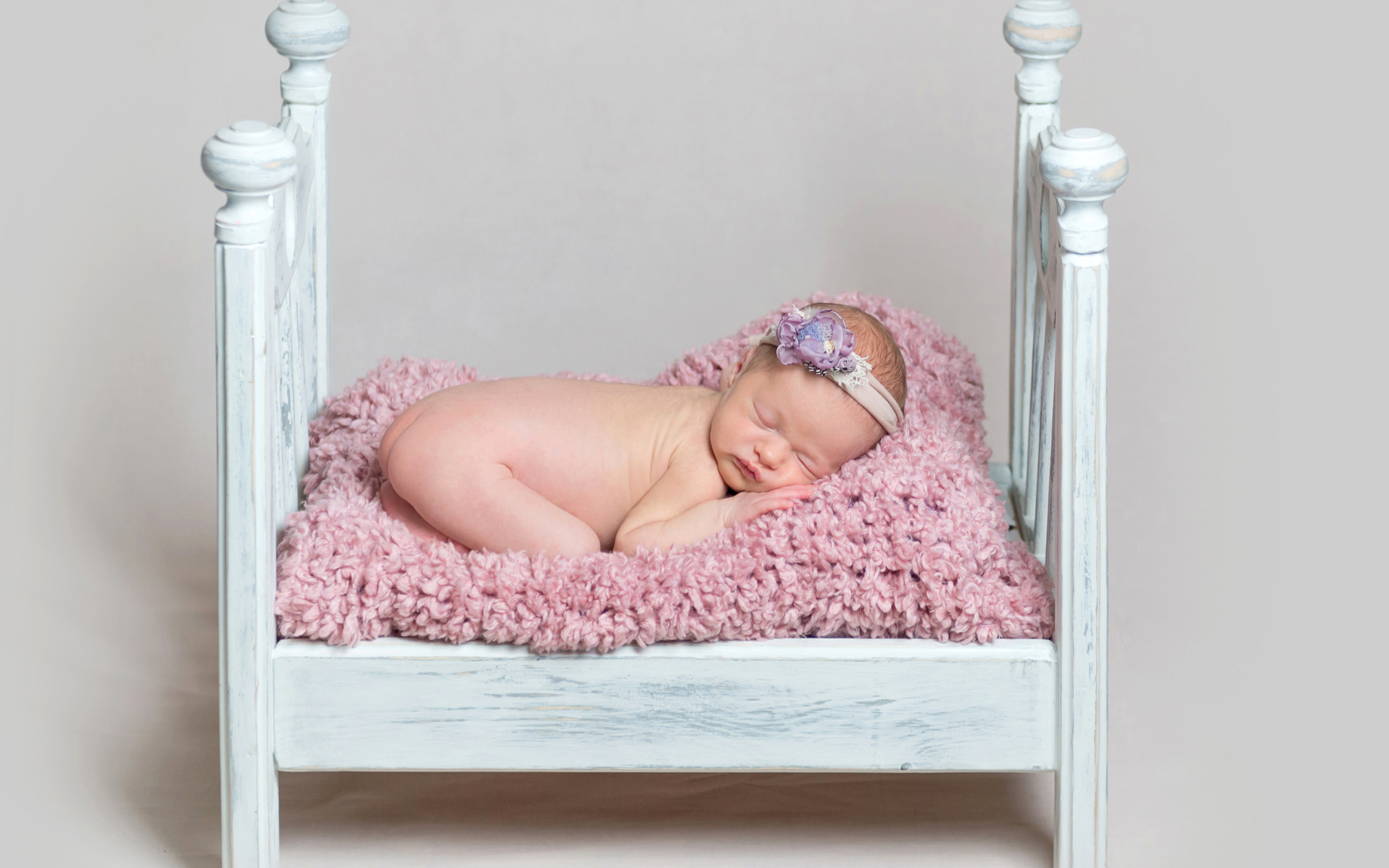 Милый грудной ребенок спит в маленькой кроватке на сером фоне