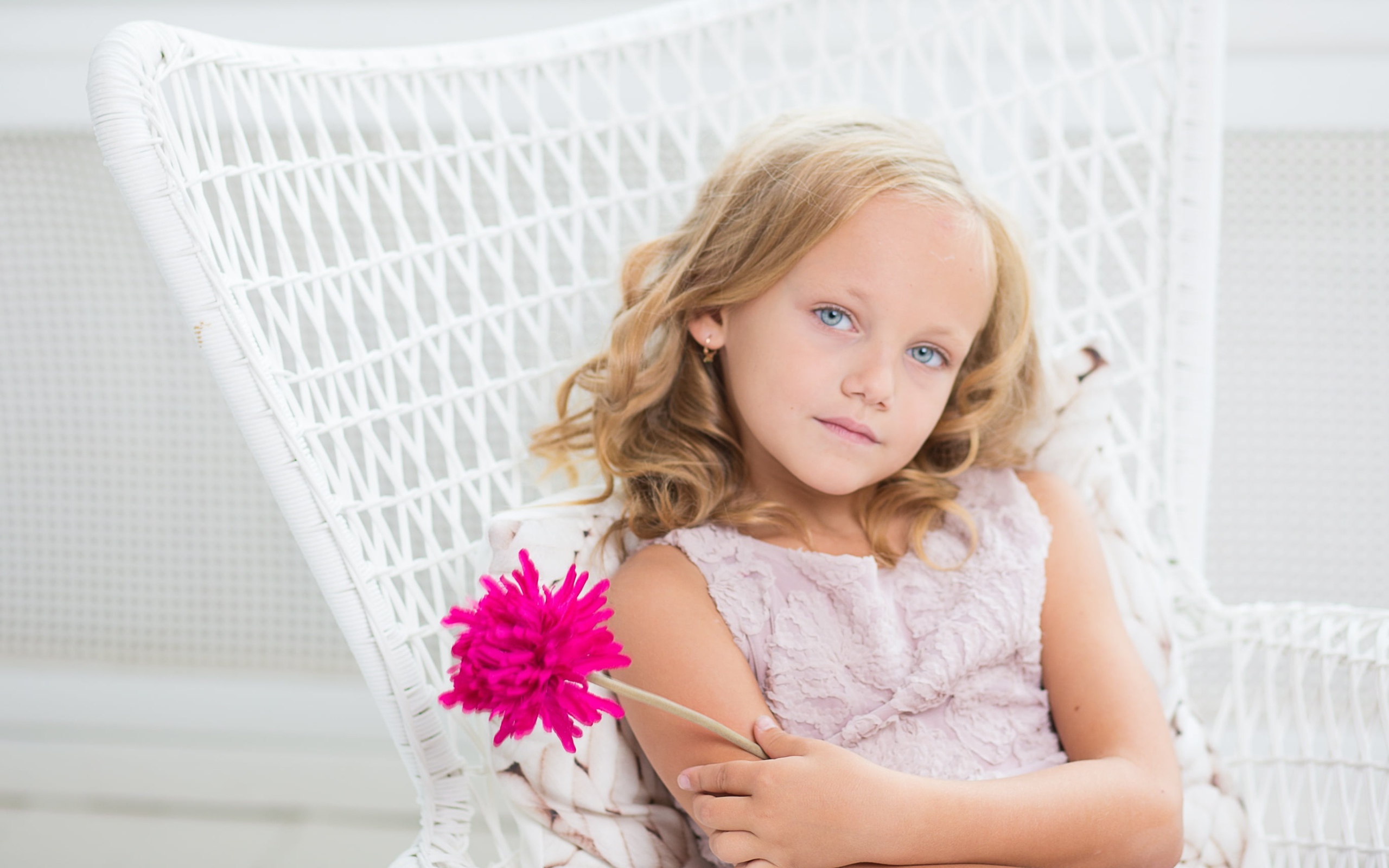 Маленькая девочка сидит в белом кресле с розовым цветком