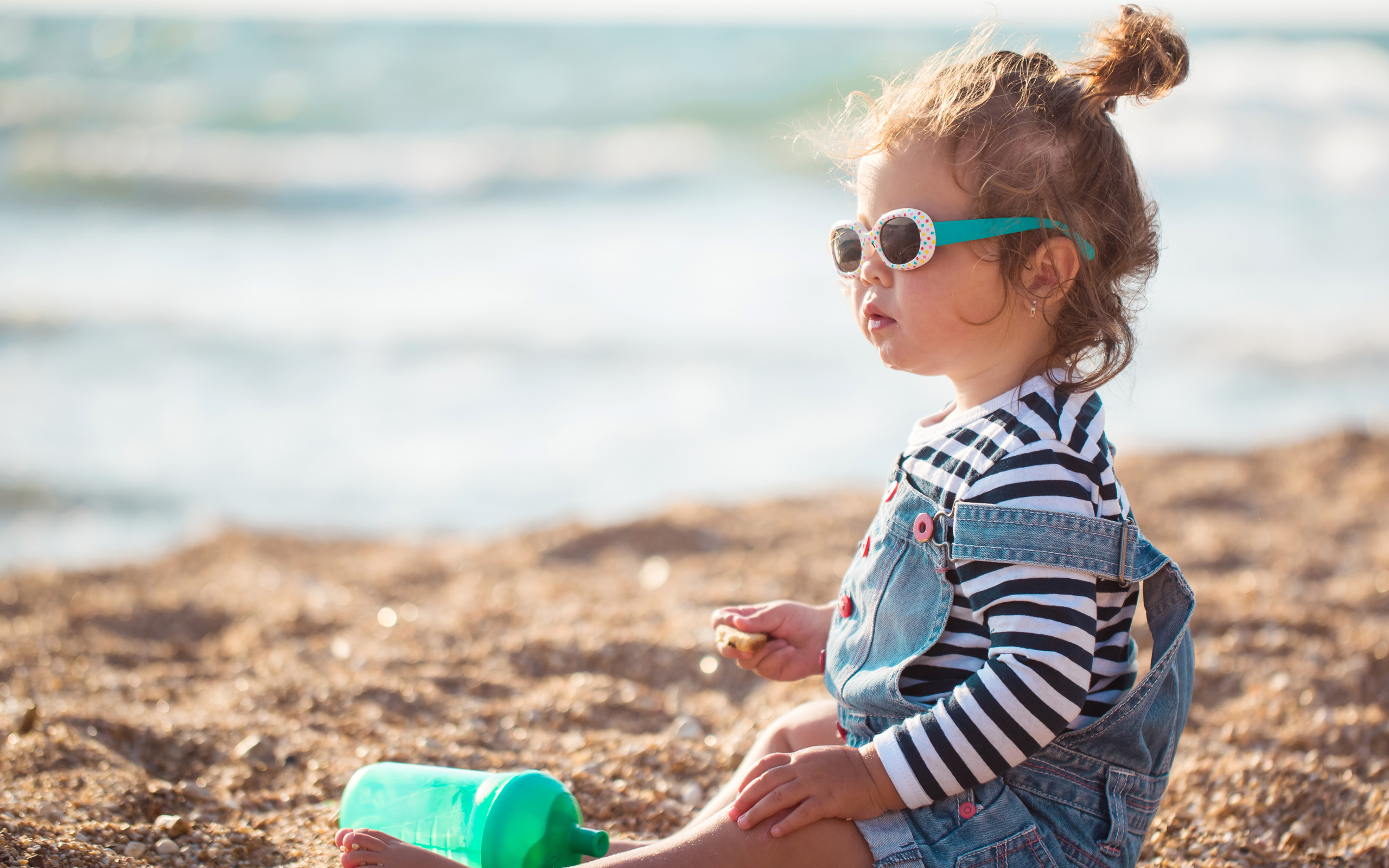 Маленькая девочка сидит на песке на пляже