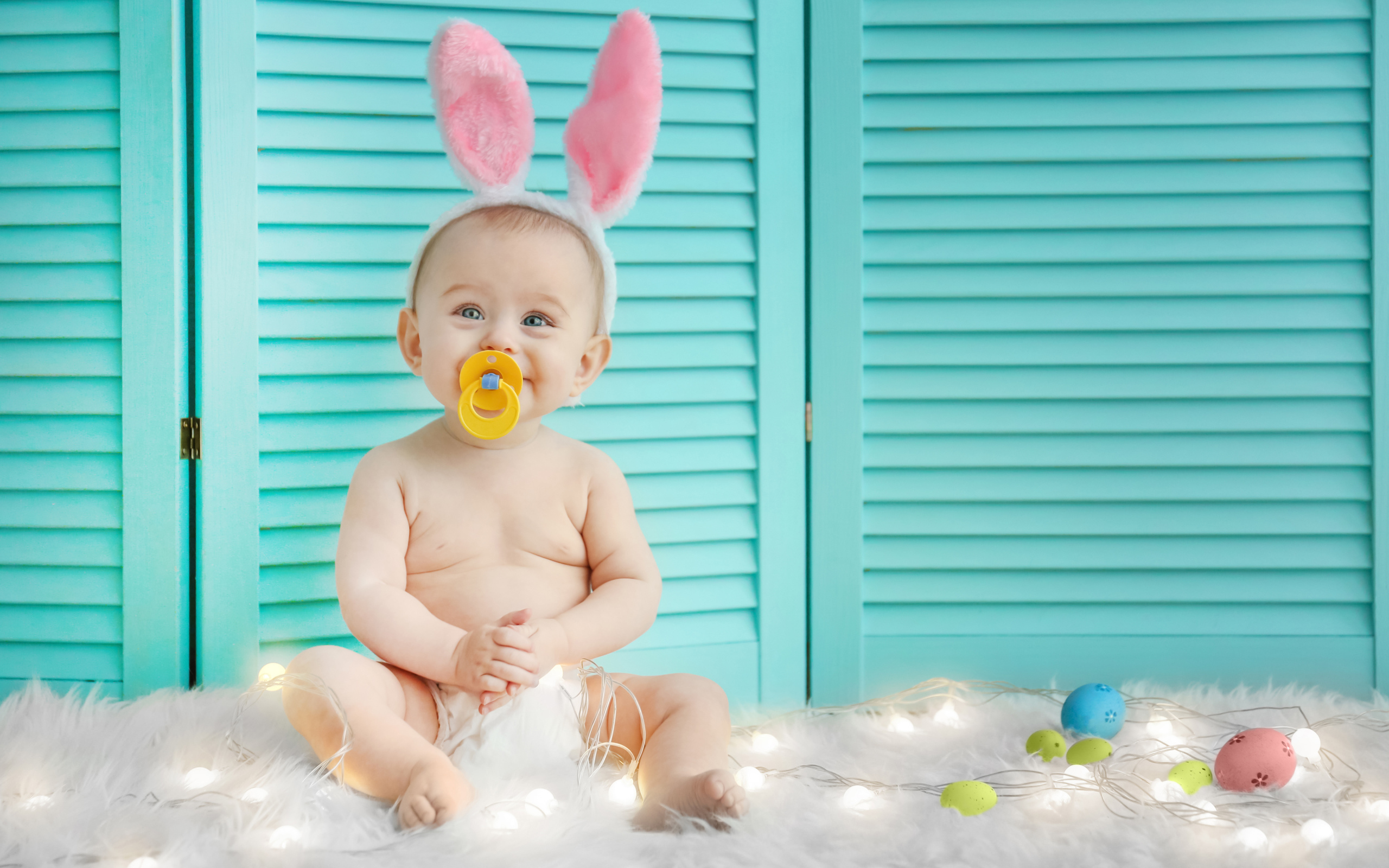 Маленький улыбающийся малыш с ушками зайчика на голове