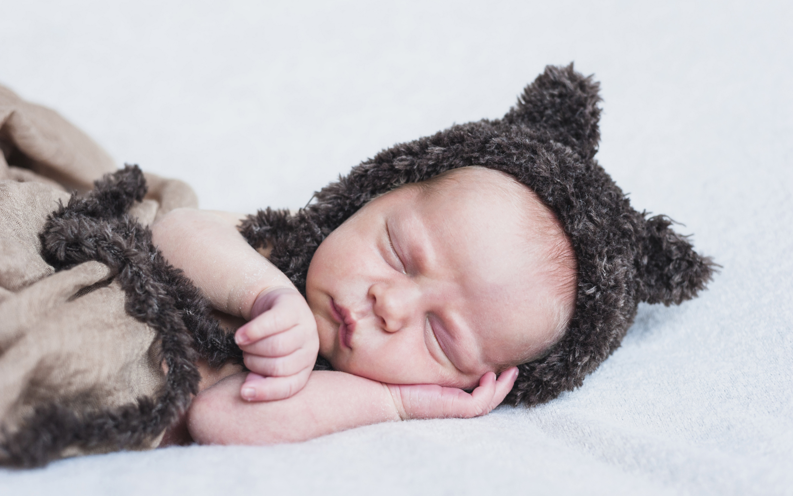 Спящий грудной ребенок в меховой шапке