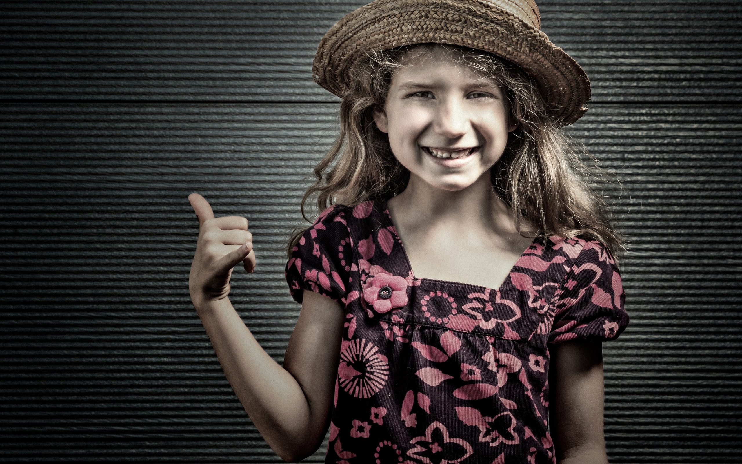 Улыбающаяся девочка в соломенной шляпе у стены 