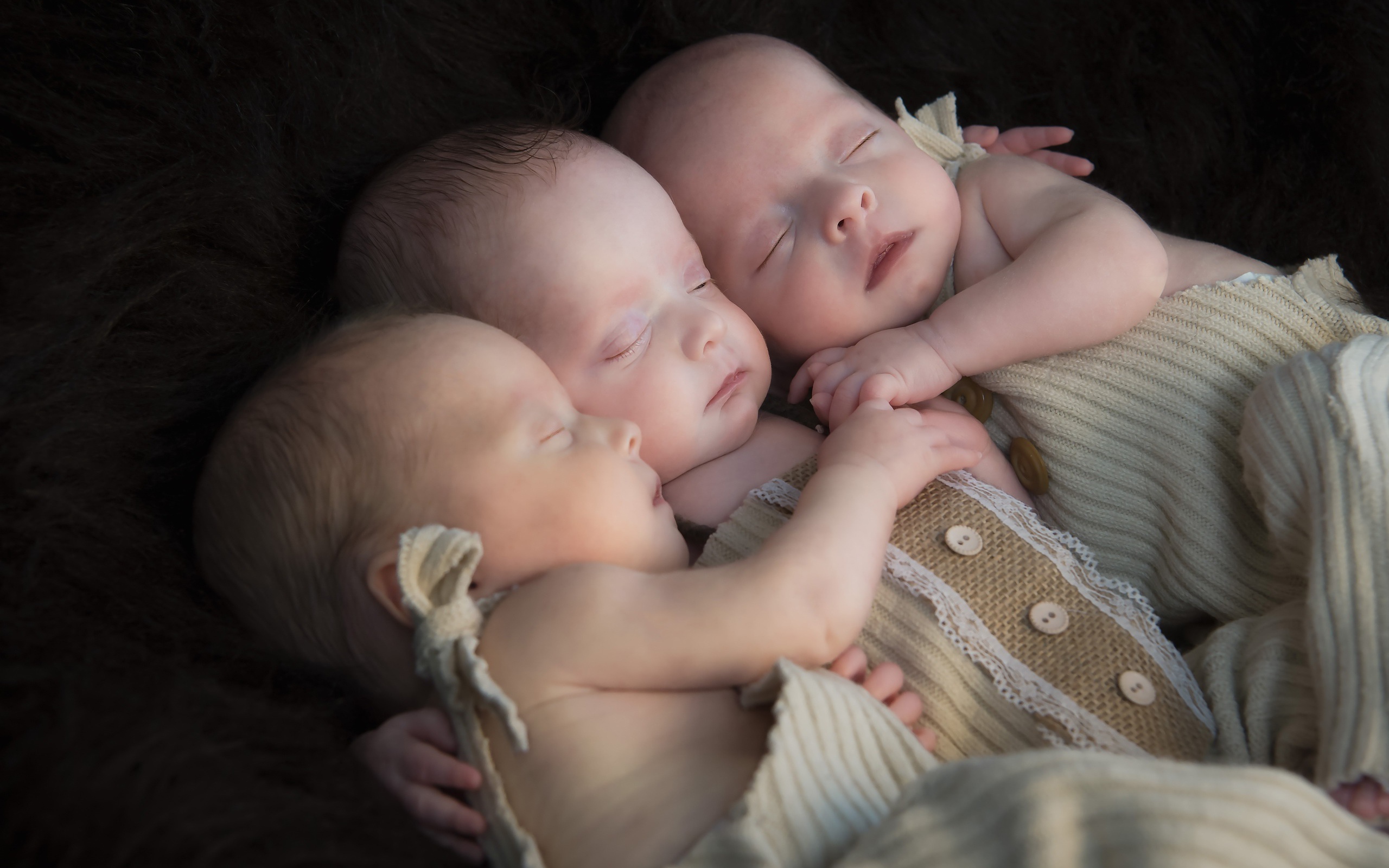 Три маленьких грудных ребенка спят обнявшись 
