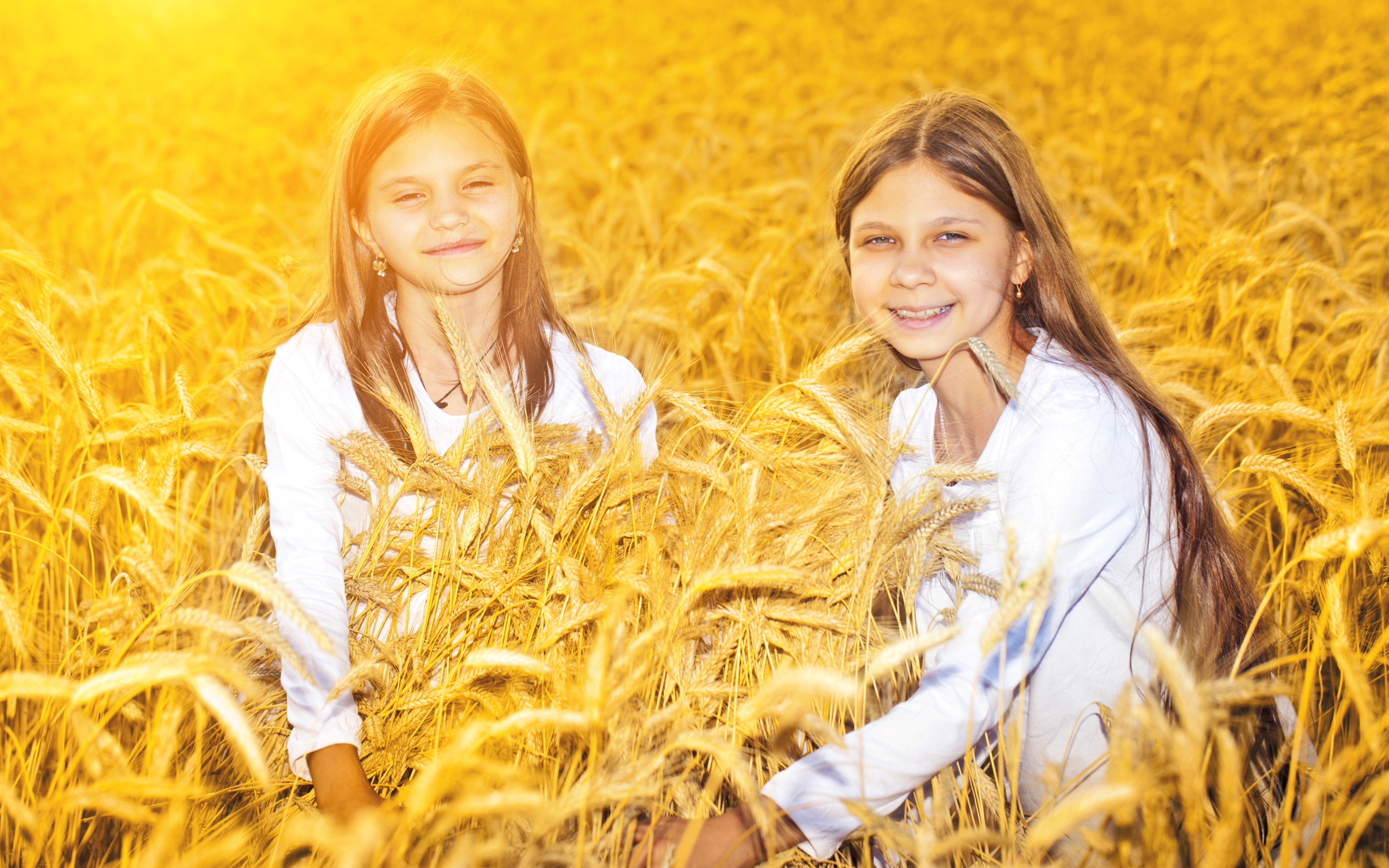 Две улыбающиеся девочки на поле с пшеницей