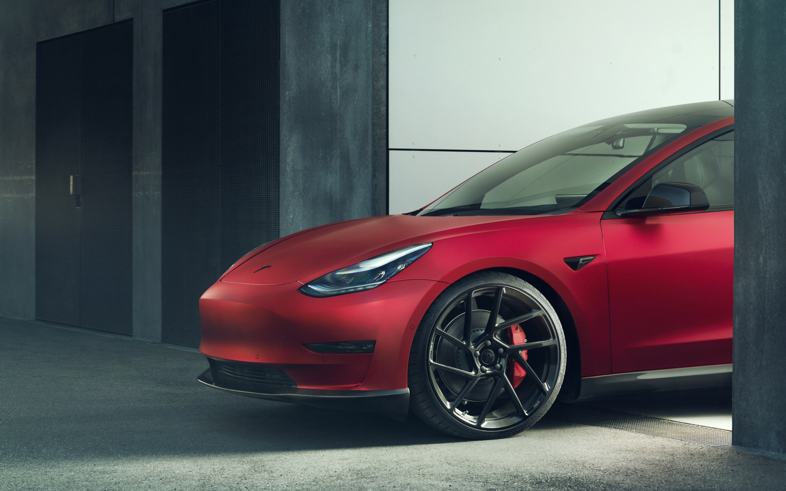 Красный автомобиль Tesla Model 3 2019 года выезжает в гаража