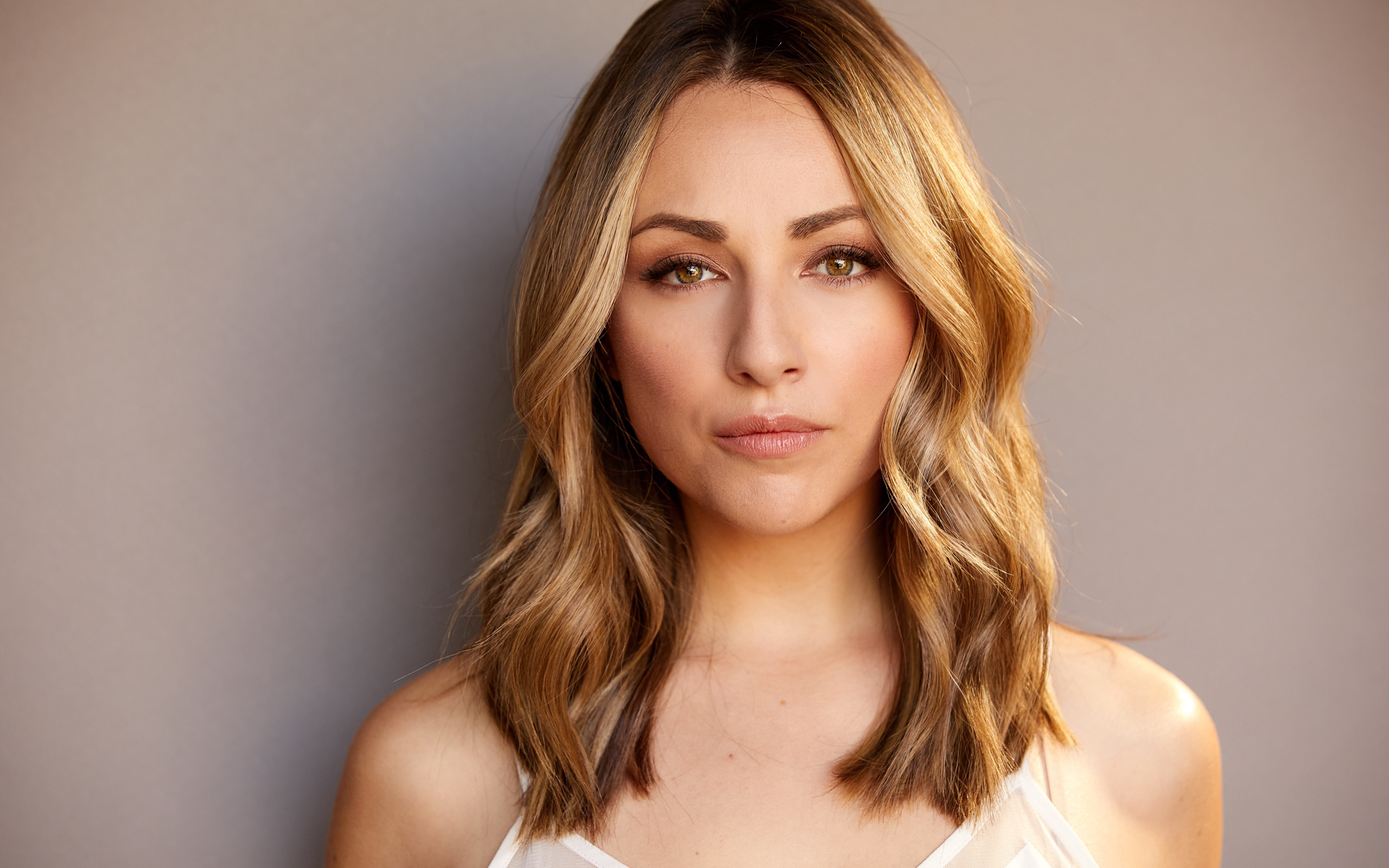 Красивая блондинка Никки Поснер на сером фоне 