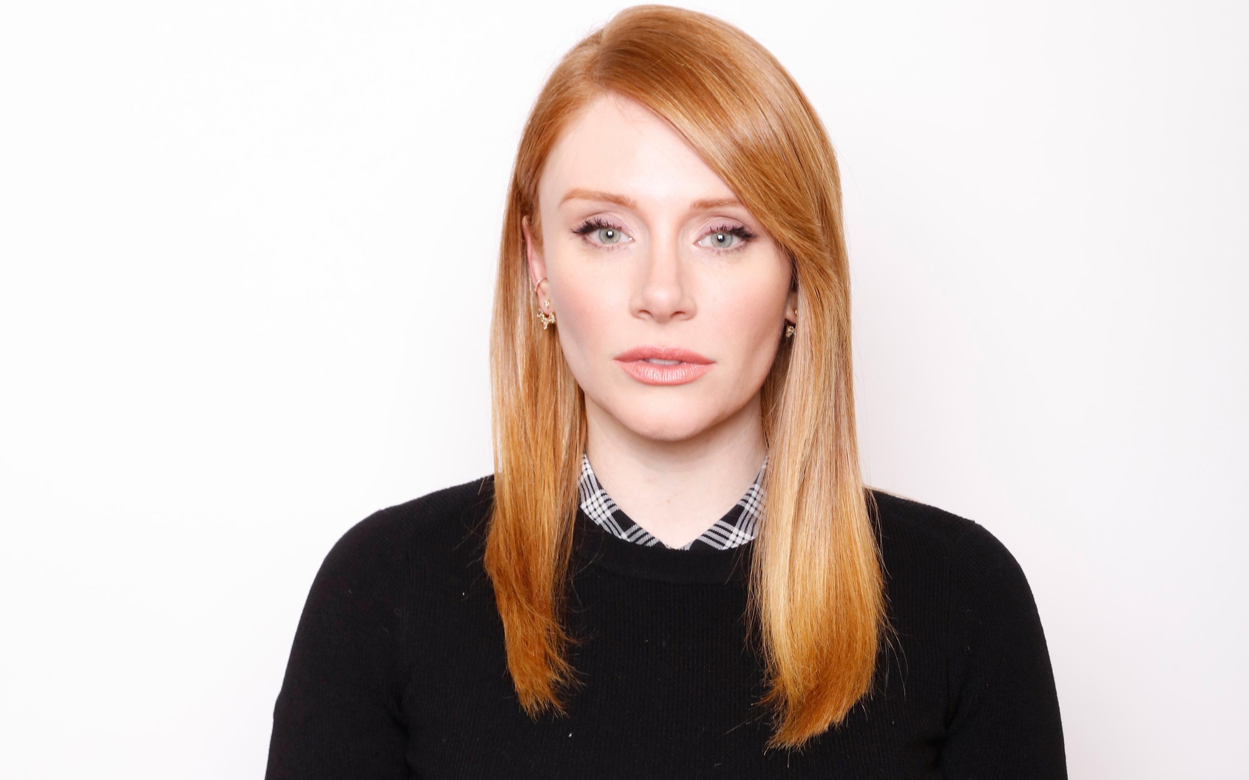 Рыжеволосая актриса Брайс Даллас Ховард в черном свитере на белом фоне
