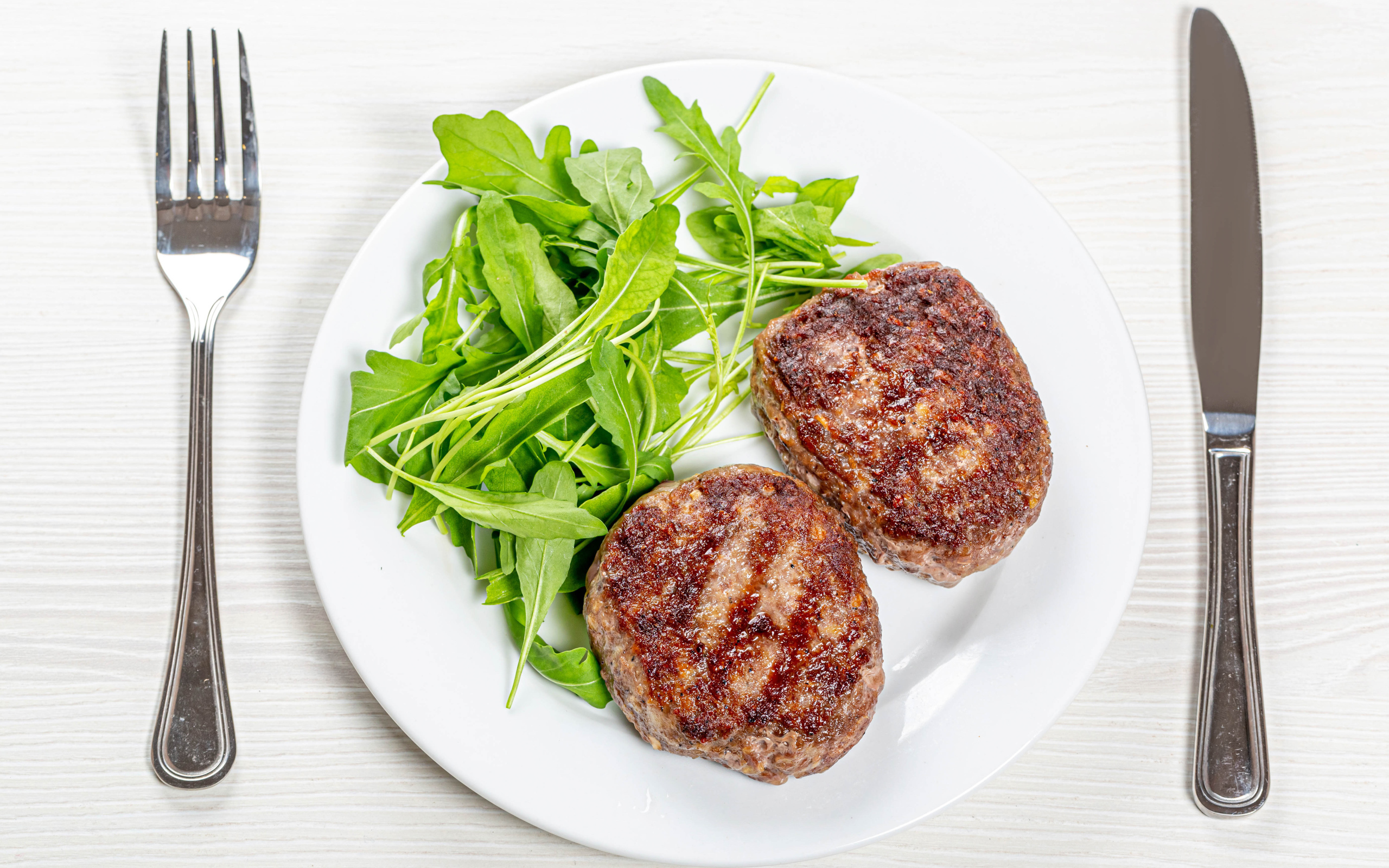 Две котлеты на тарелке с зеленью рукколы 