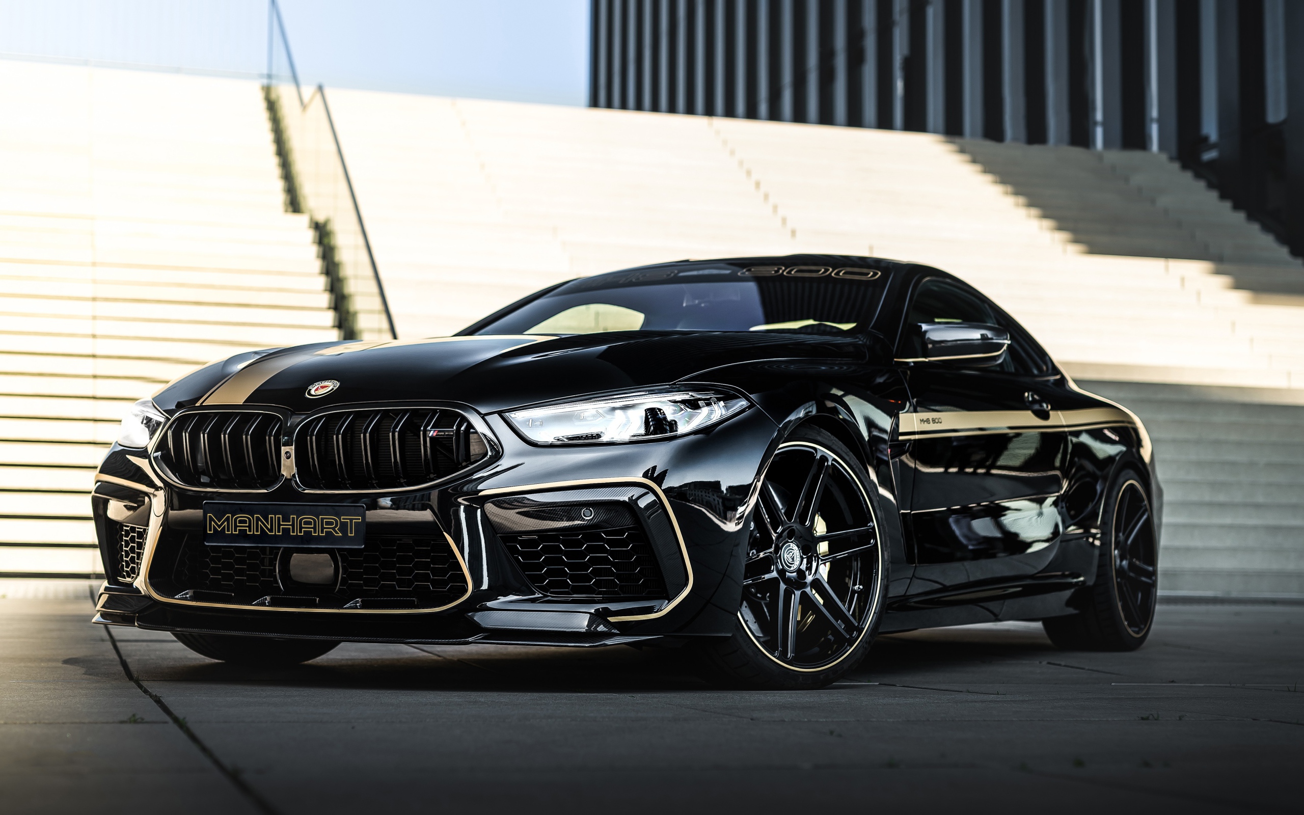 Черный автомобиль BMW Manhart MH8 800 2020 года у лестницы 