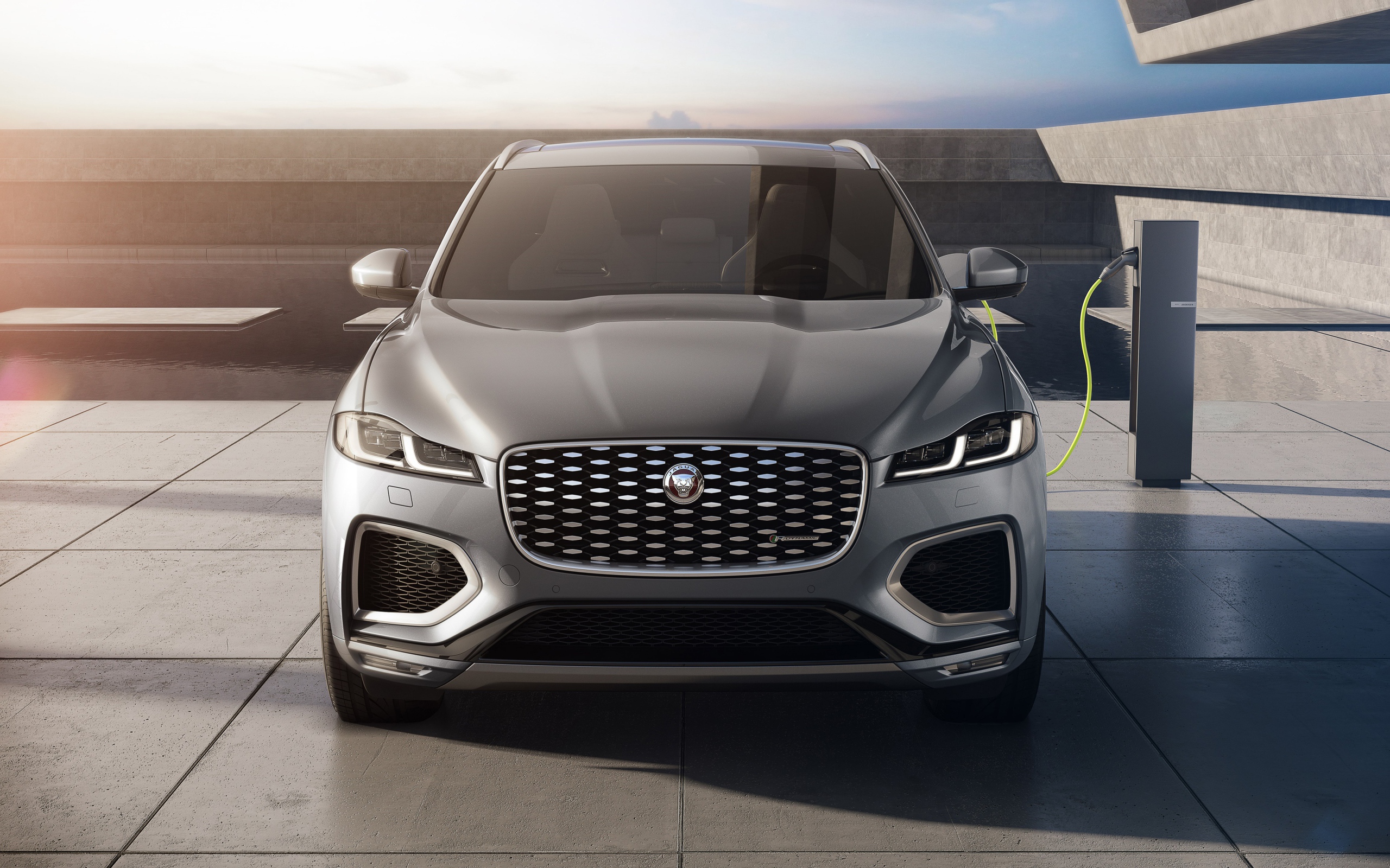 Серый автомобиль Jaguar F-Pace P400e AWD 2020 года на заправке