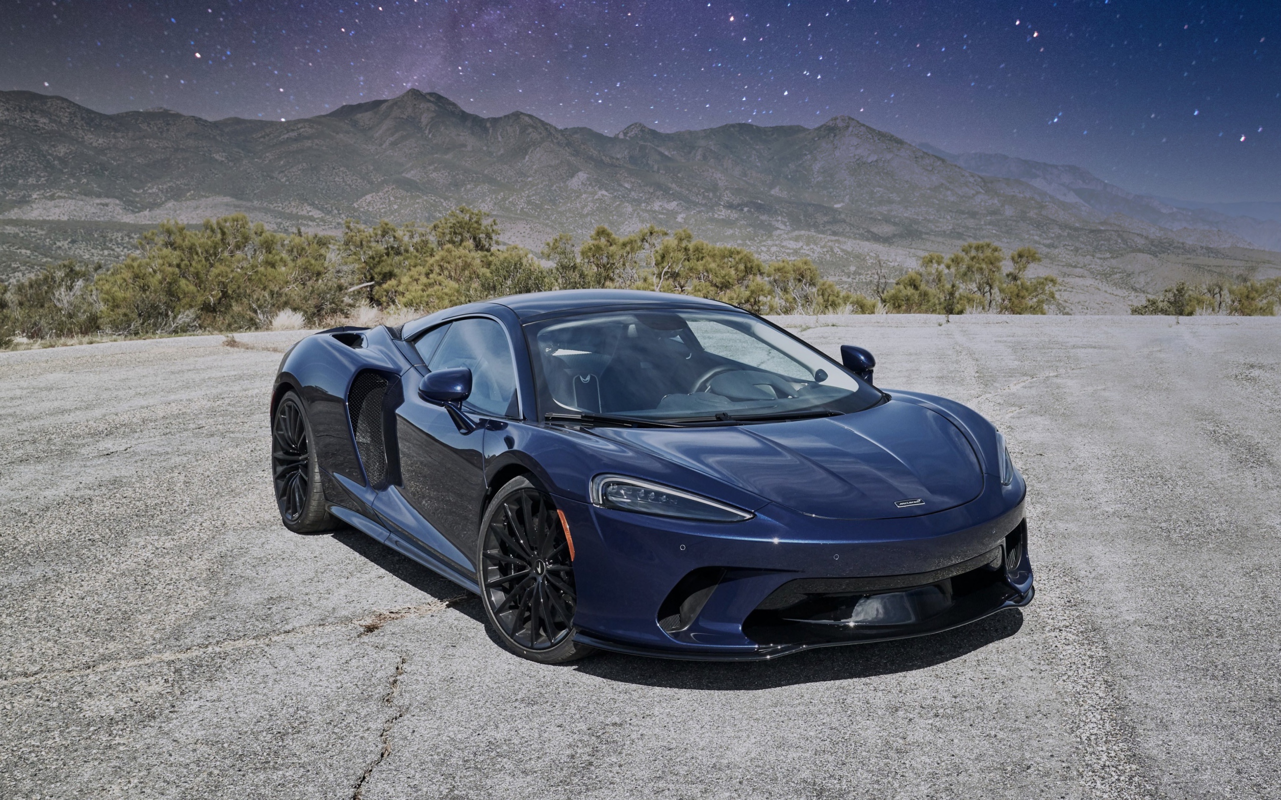 Черный автомобиль  McLaren GT, 2020 года под звездным небом