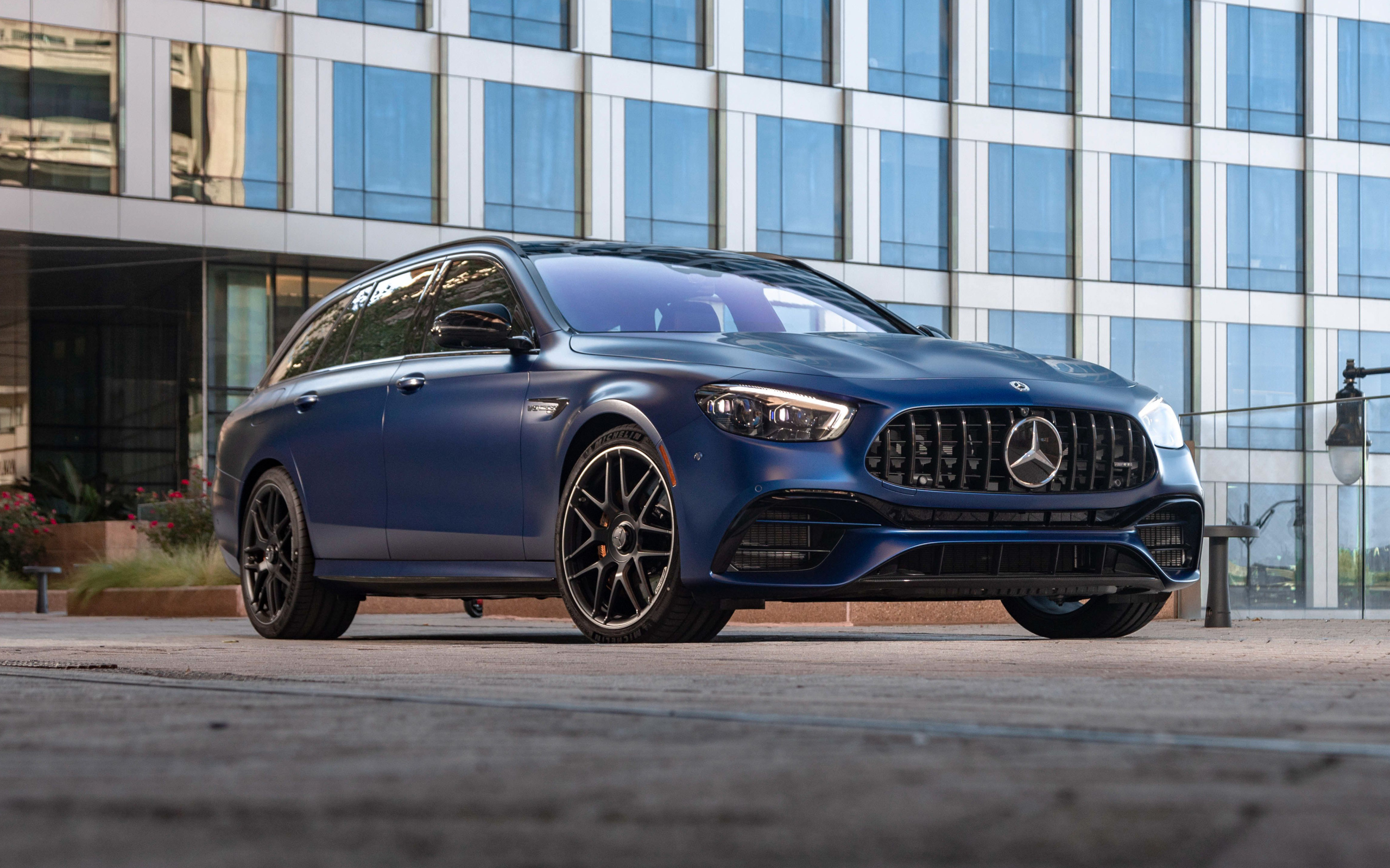 Синий автомобиль Mercedes-AMG E 63 S 4MATIC+, 2021 года на фоне дома