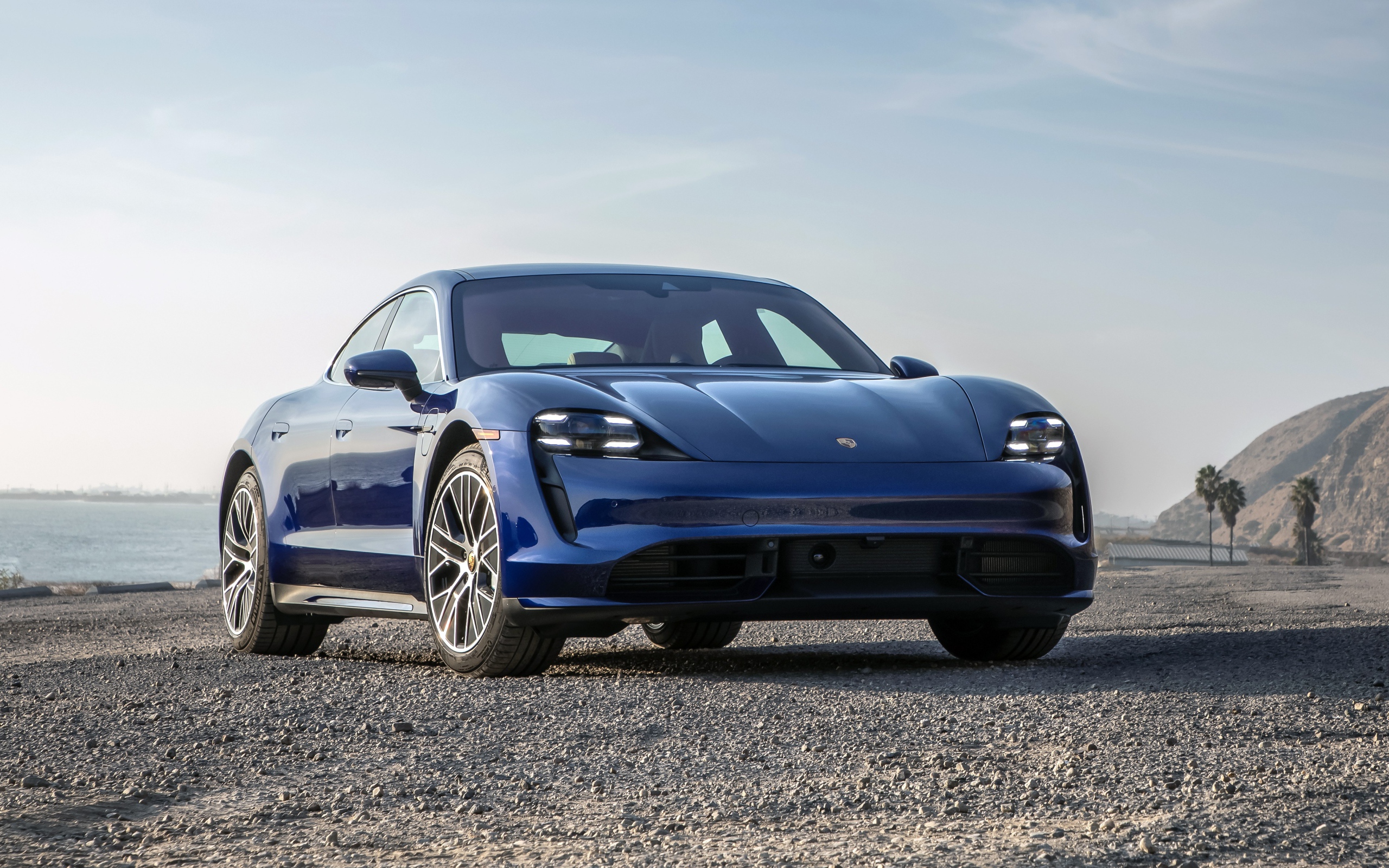Синий автомобиль  Porsche Taycan Turbo, 2020 года у океана