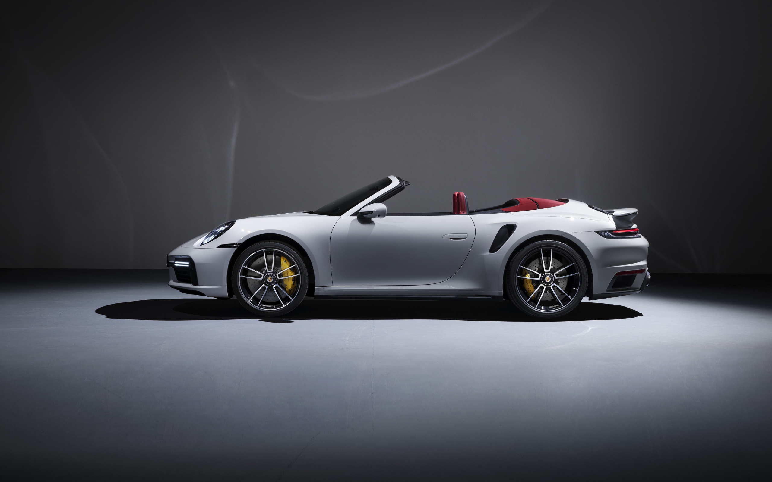 Белый автомобиль Porsche 911 Turbo S Cabriolet 2020 года на сером фоне