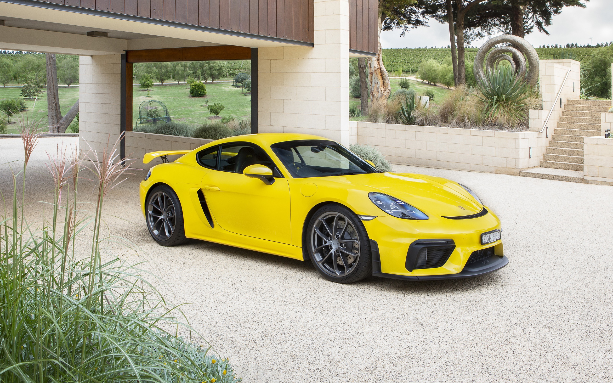 Желтый автомобиль Porsche 718 Cayman GT4, 2020 года у дома