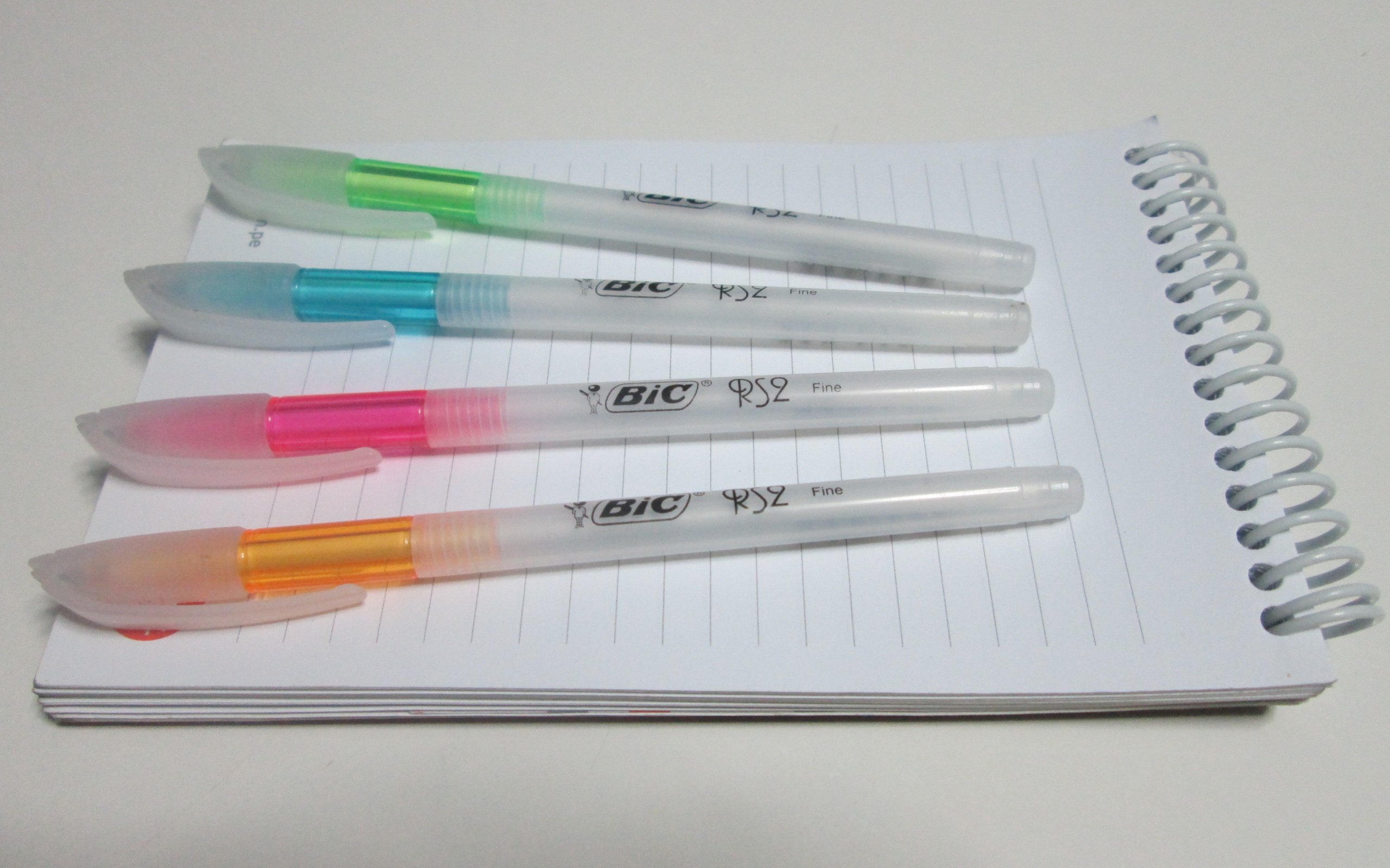 Multi-colored pens lie on a notebook on a white background