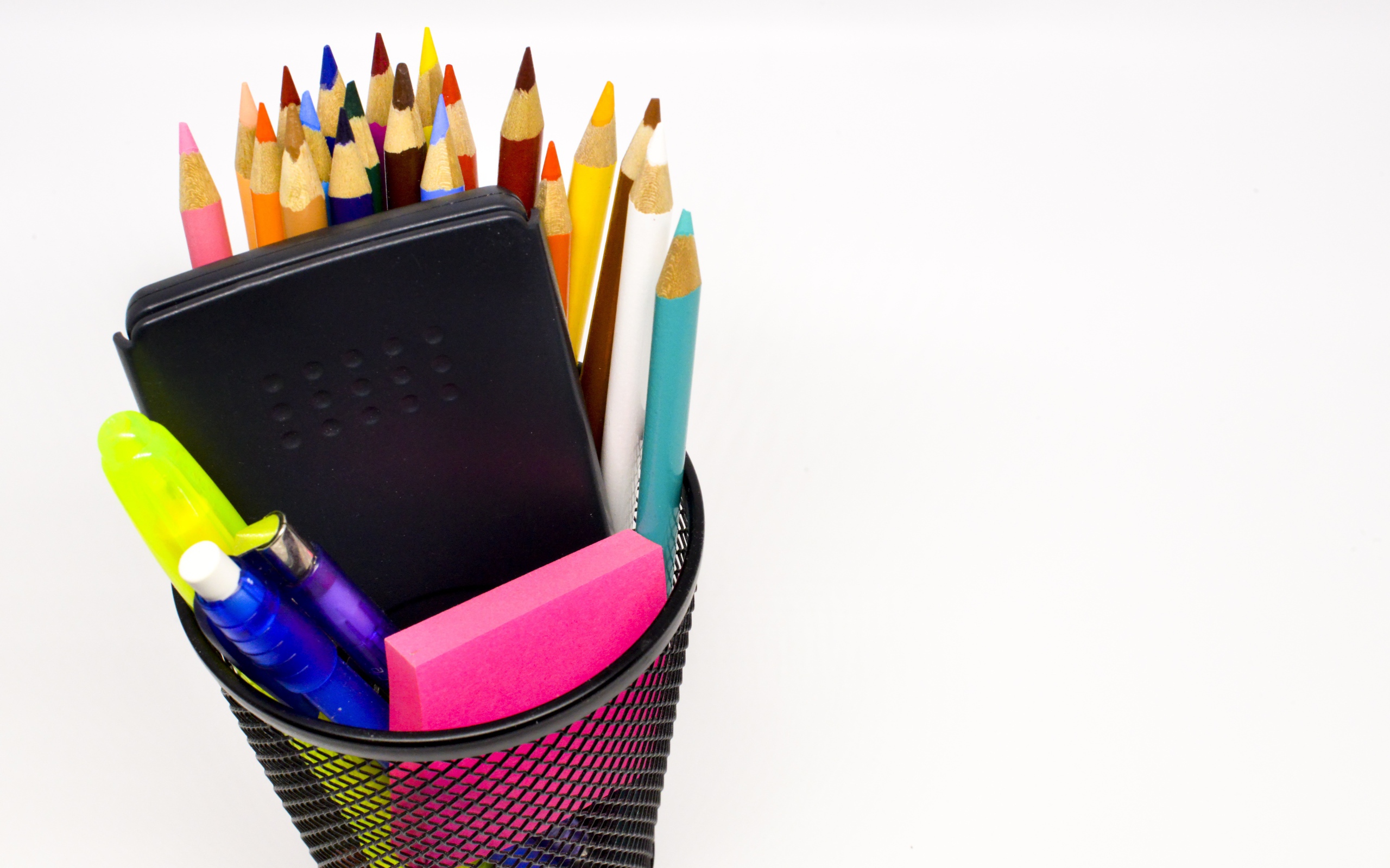 Канцелярские предметы в черном стакане на белом фоне 