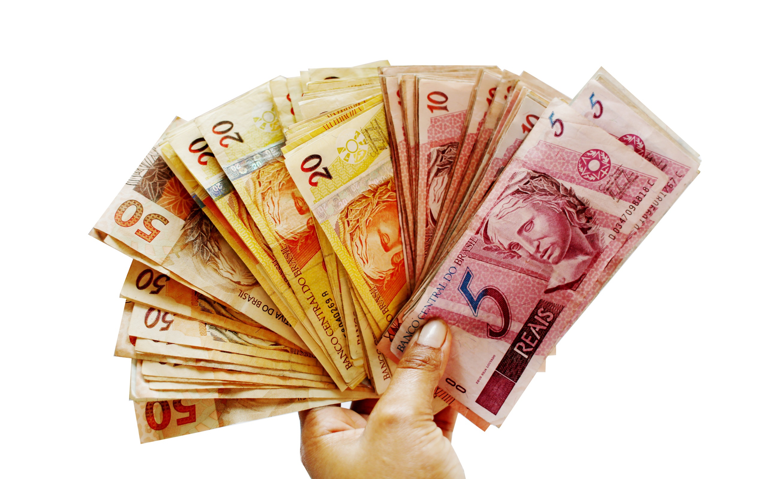 Много купюр бразильского реала в руке на белом фоне 