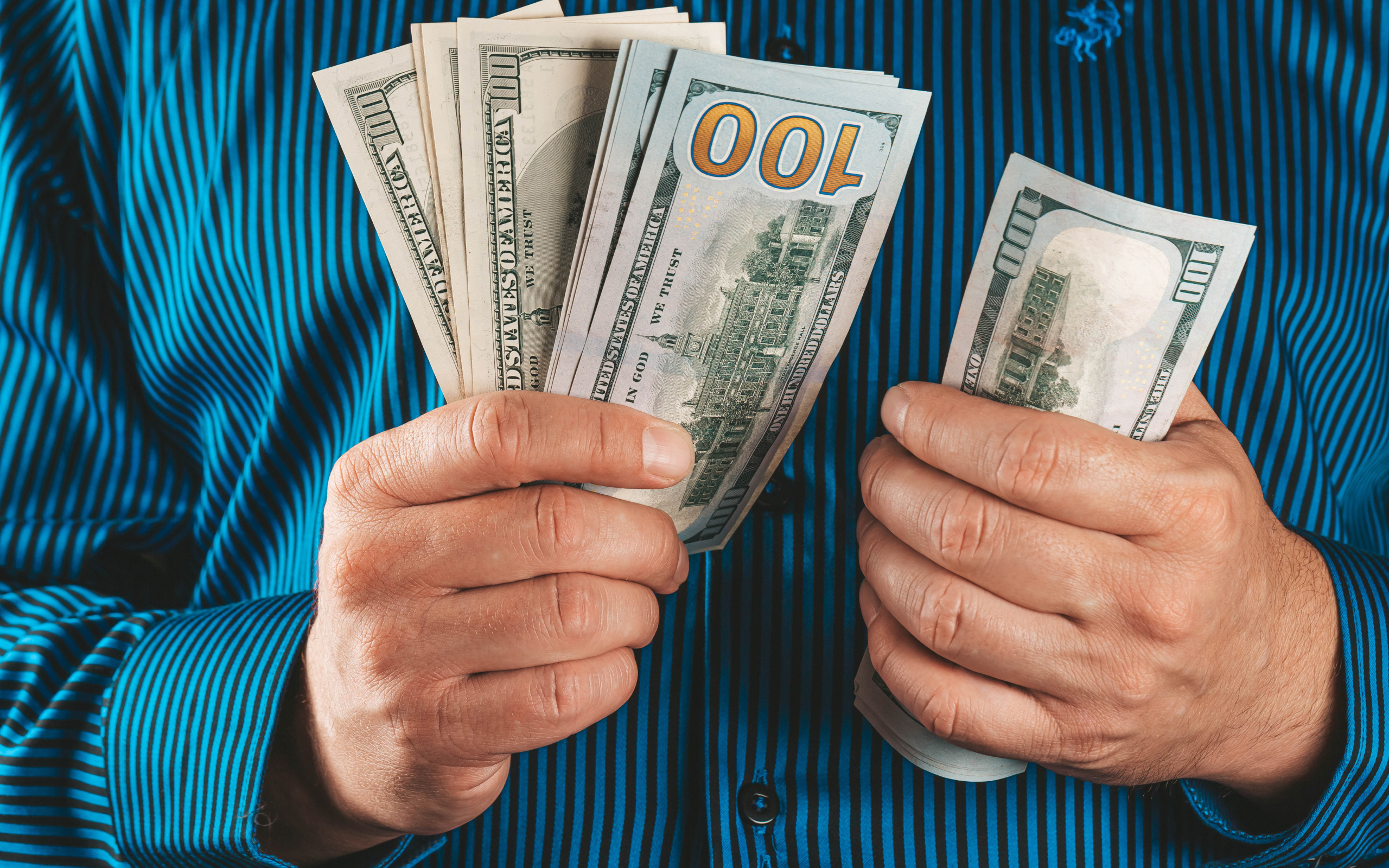 Мужчина считает сто долларовые купюры 