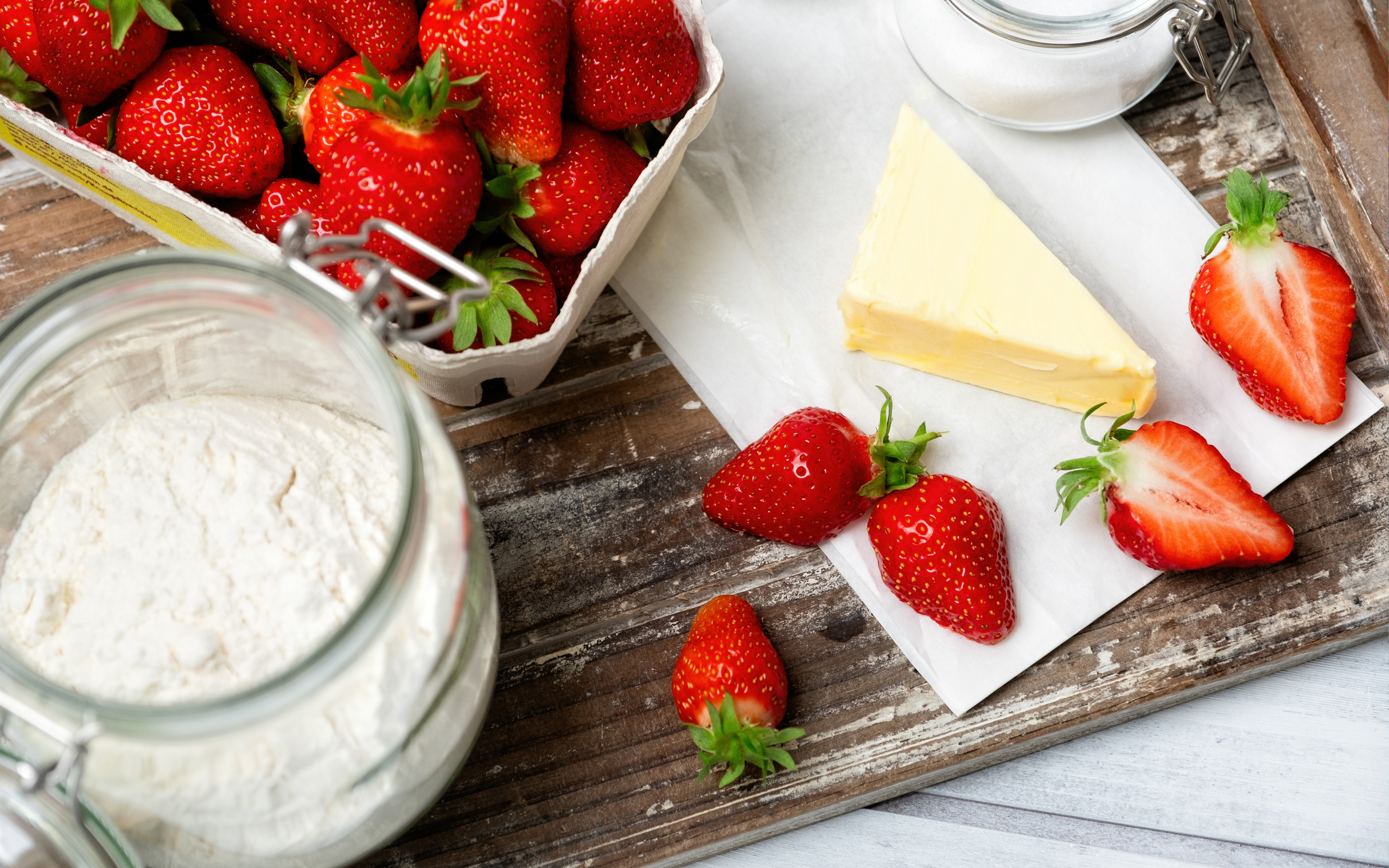 Кусок масла на столе с клубникой и мукой 