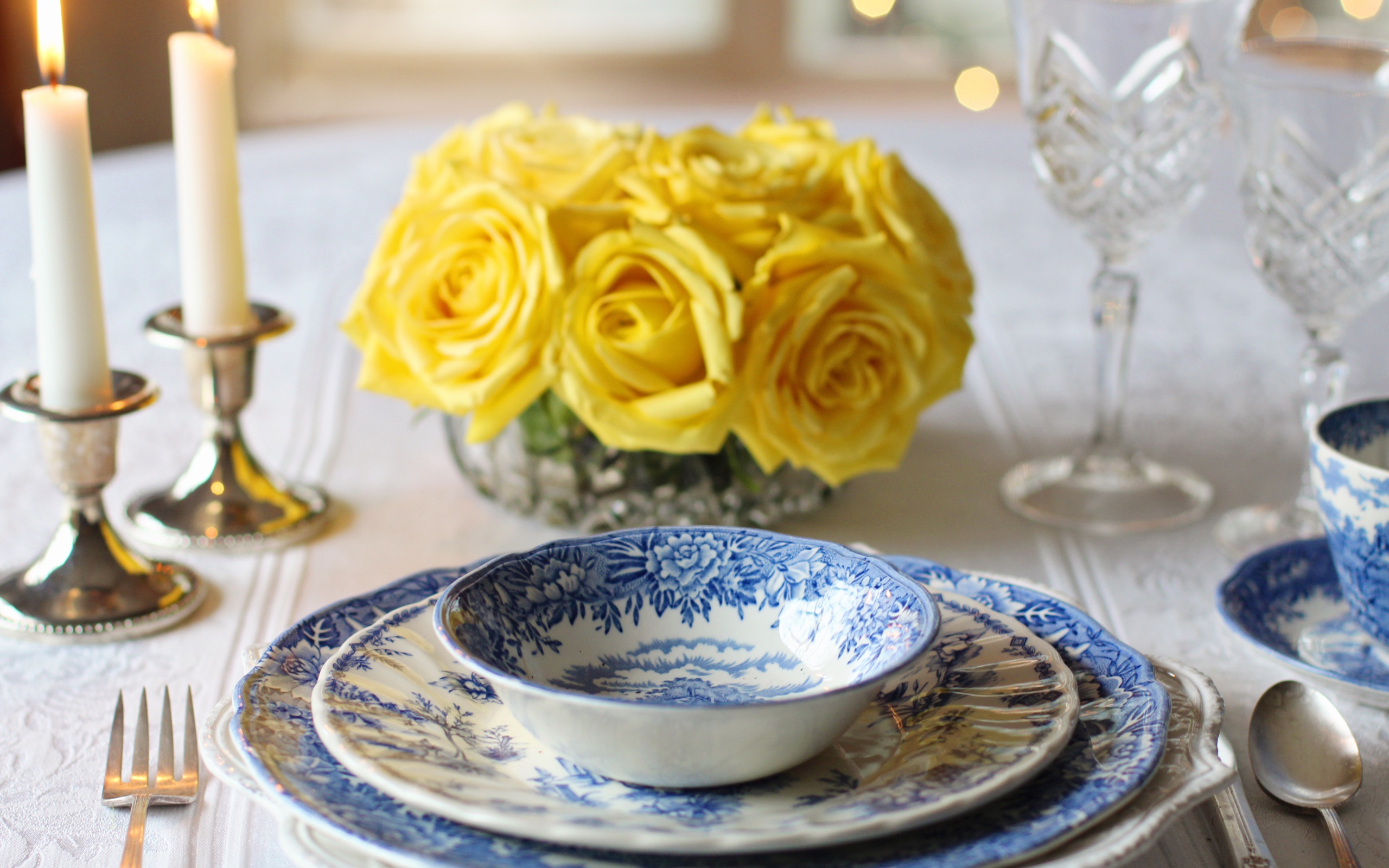 Красивая посуда на столе с букетом роз и свечами