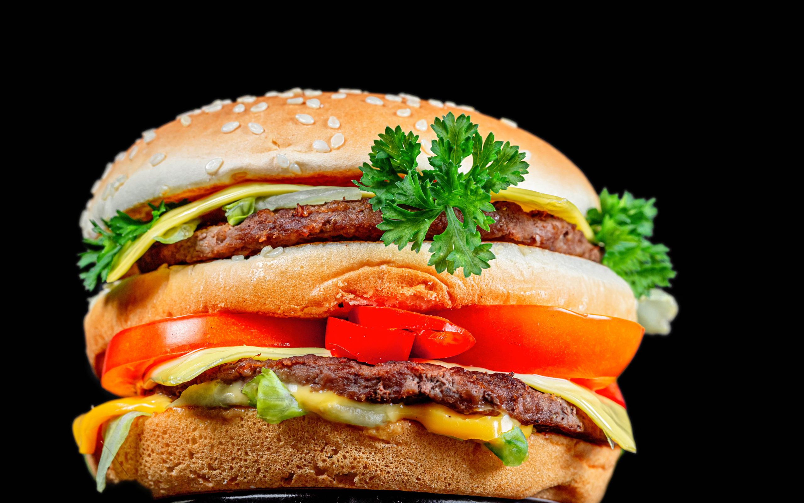 Большой гамбургер с котлетой на черном фоне