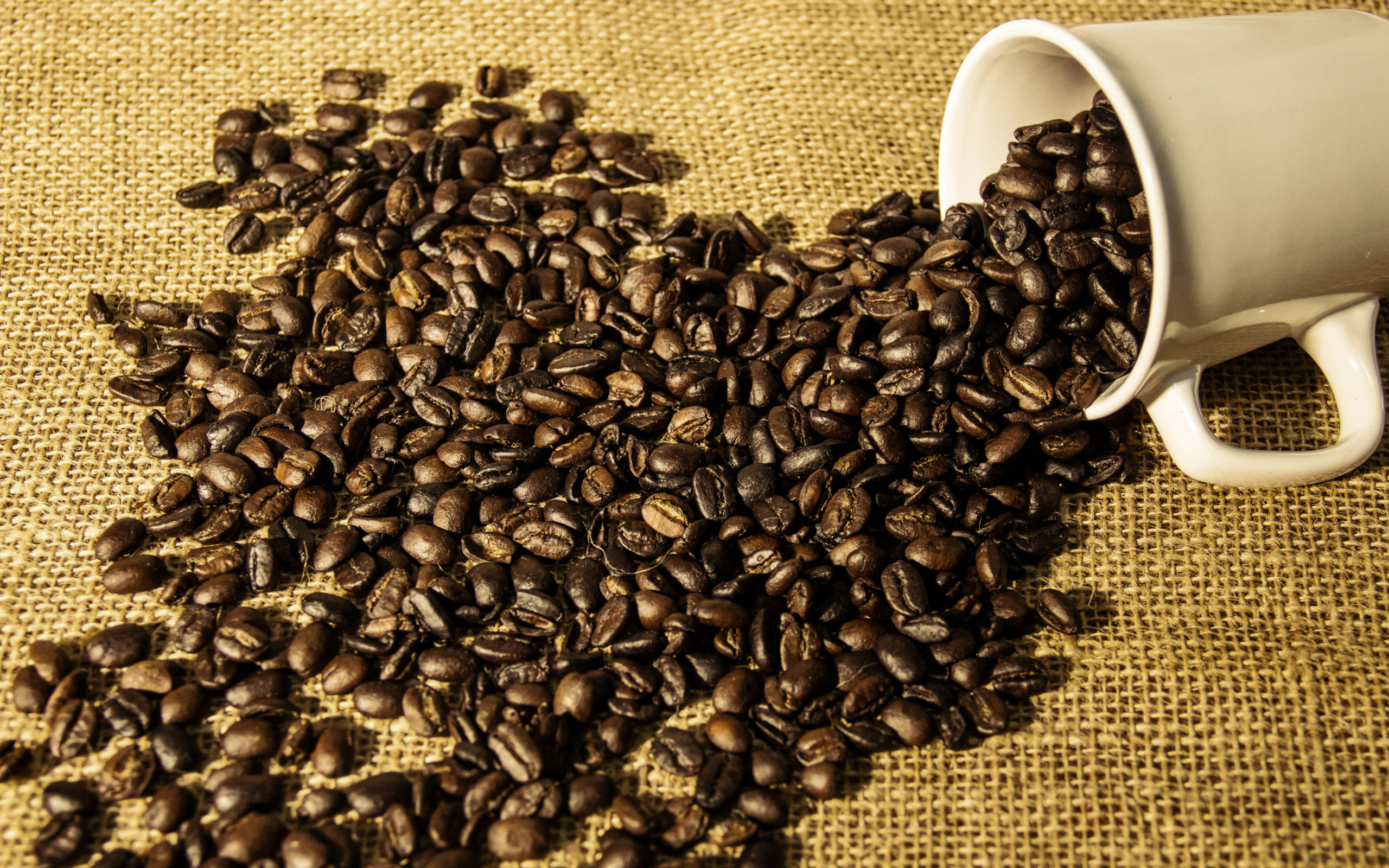 Кофейные зерна высыпаются из белой чашки 