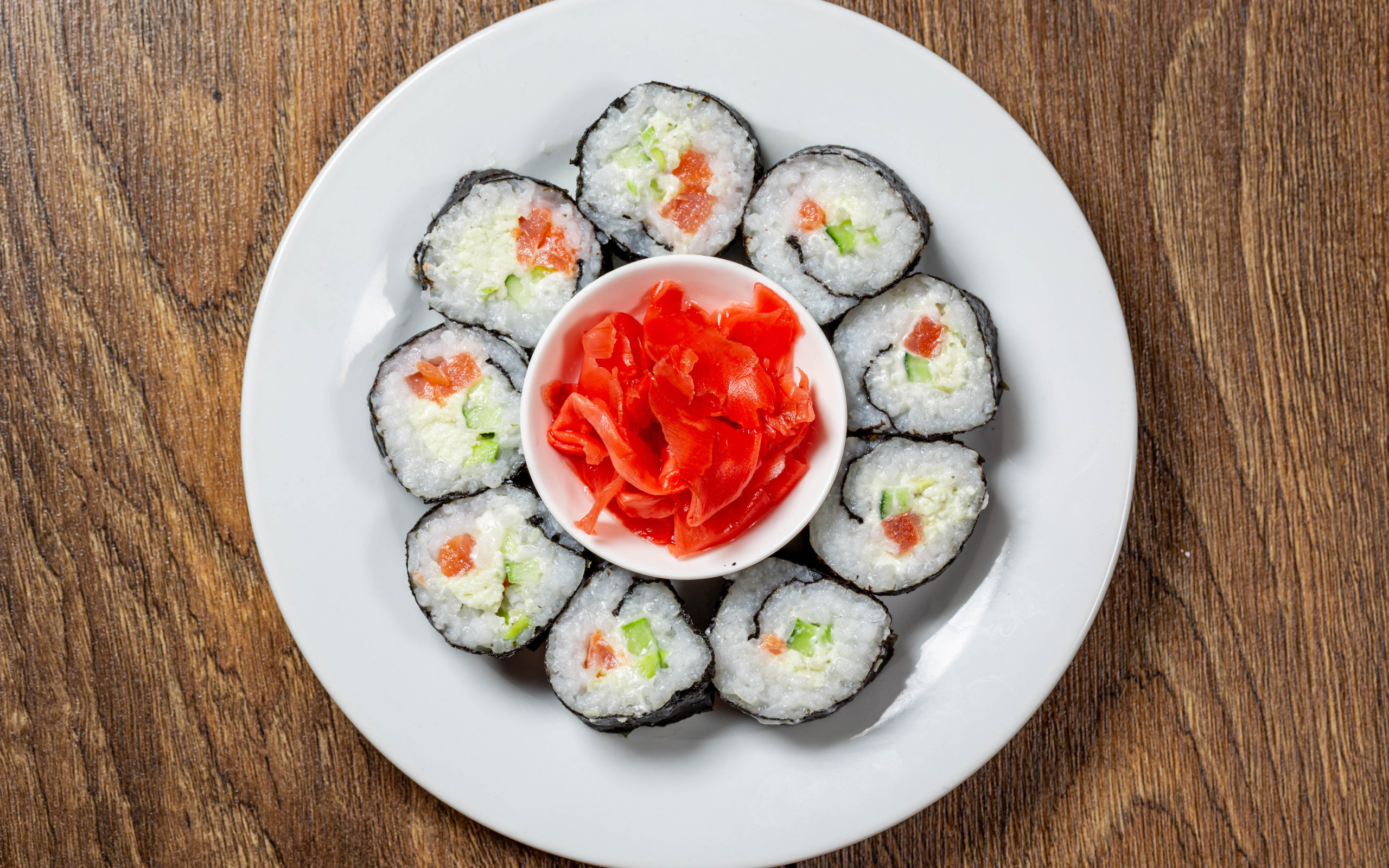 Вкусные суши на большой белой тарелке с имбирем