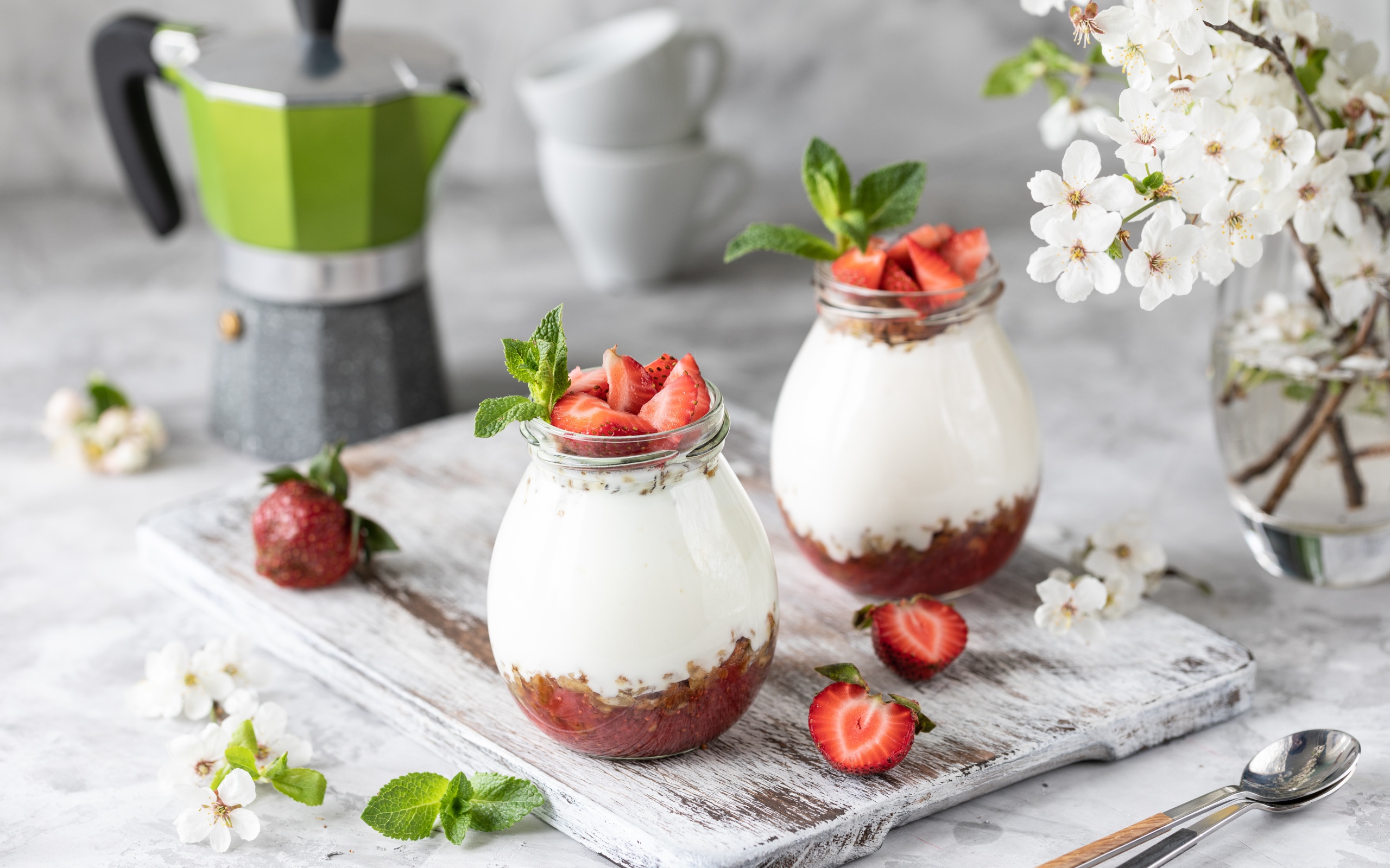 Десерт с йогуртом в банке с клубникой на столе цветами вишни 